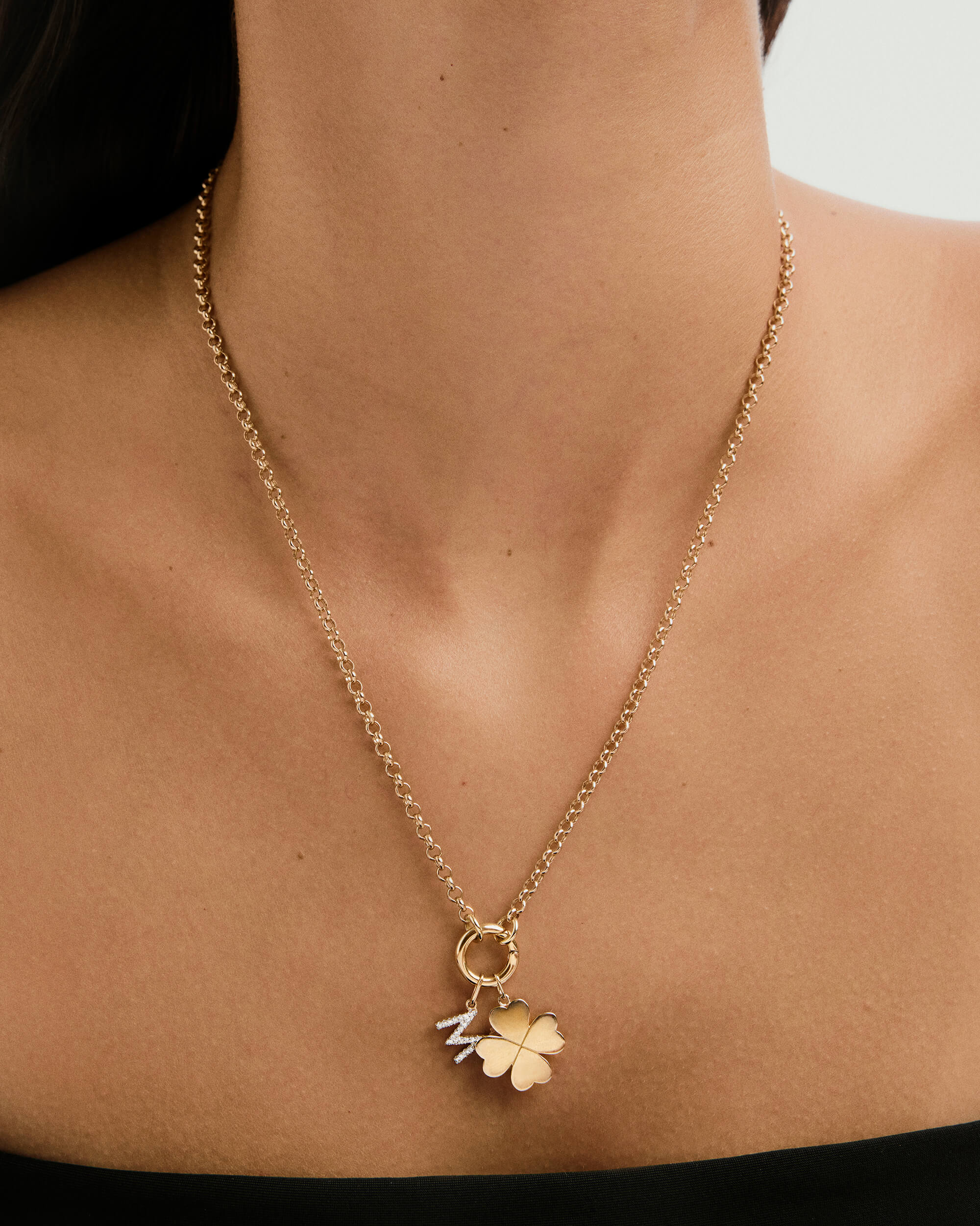 Flat Clover Charm necklace elegantly displayed on a woman's neck, featuring a gold clover adorned with diamonds, exemplifying a playful, lucky fashion statement.