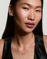 Young woman wearing the Better Half Heart Necklace, featuring a gold chain with a polished and pavÃ© diamond heart pendant above her collarbone.