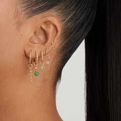 Close-up of a woman's ear wearing a Single PavÃ© Diamond Star Hoop Charm, highlighting the detailed design and sparkle of the earring.