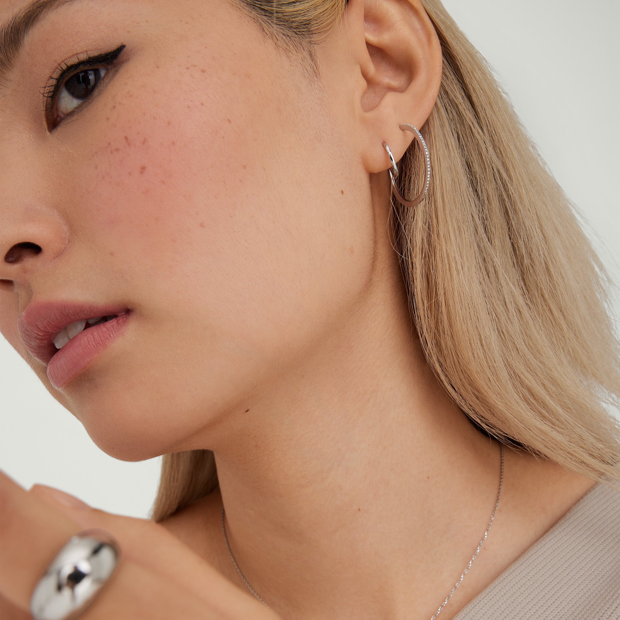 Close-up of a woman's ear wearing a Single Easy Huggie Hoop, showcasing its handcrafted 14k gold design and clicker closure.