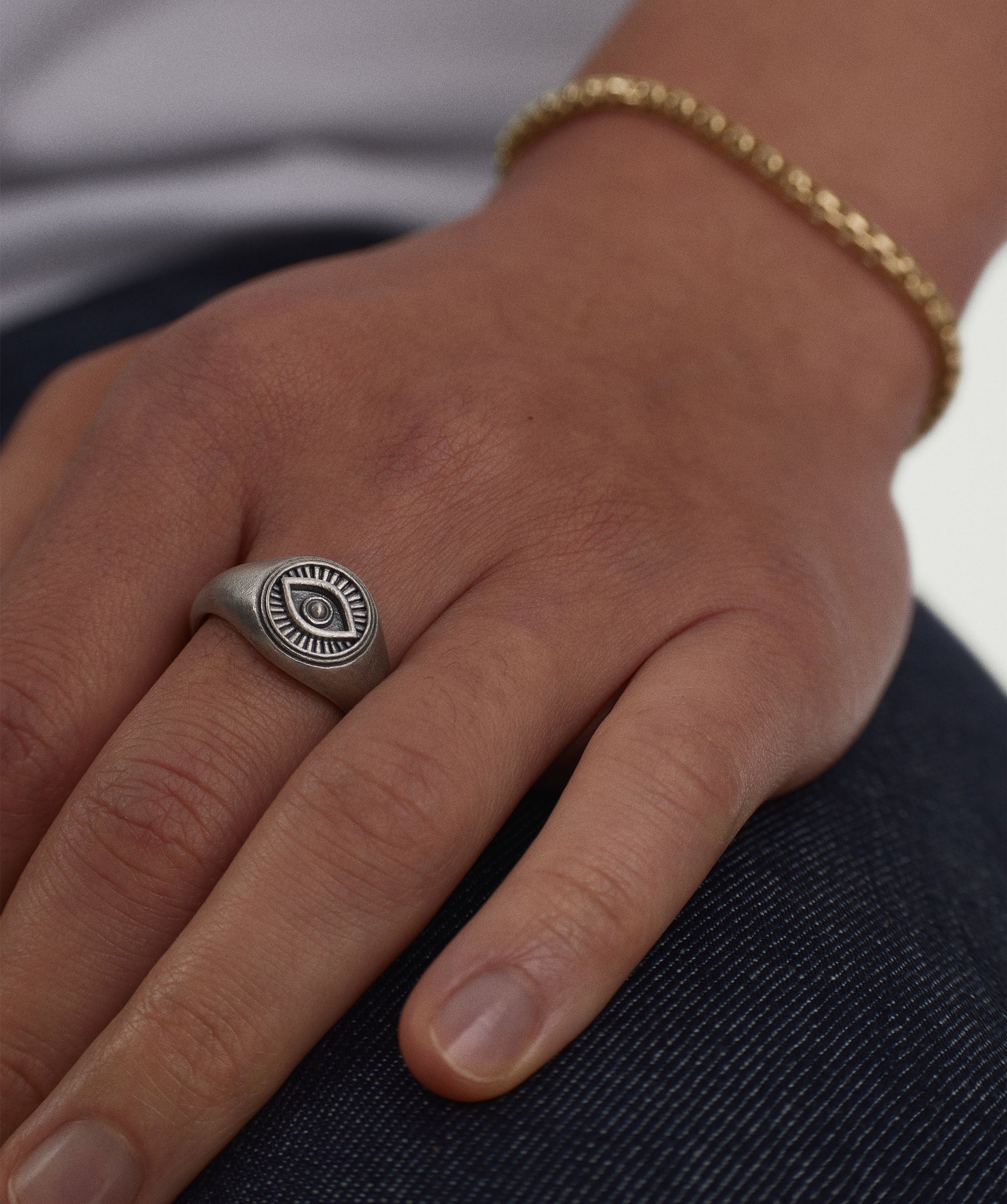 Courage Signet Ring featuring an evil eye design worn on a person's finger, symbolizing protection against envy and evil.