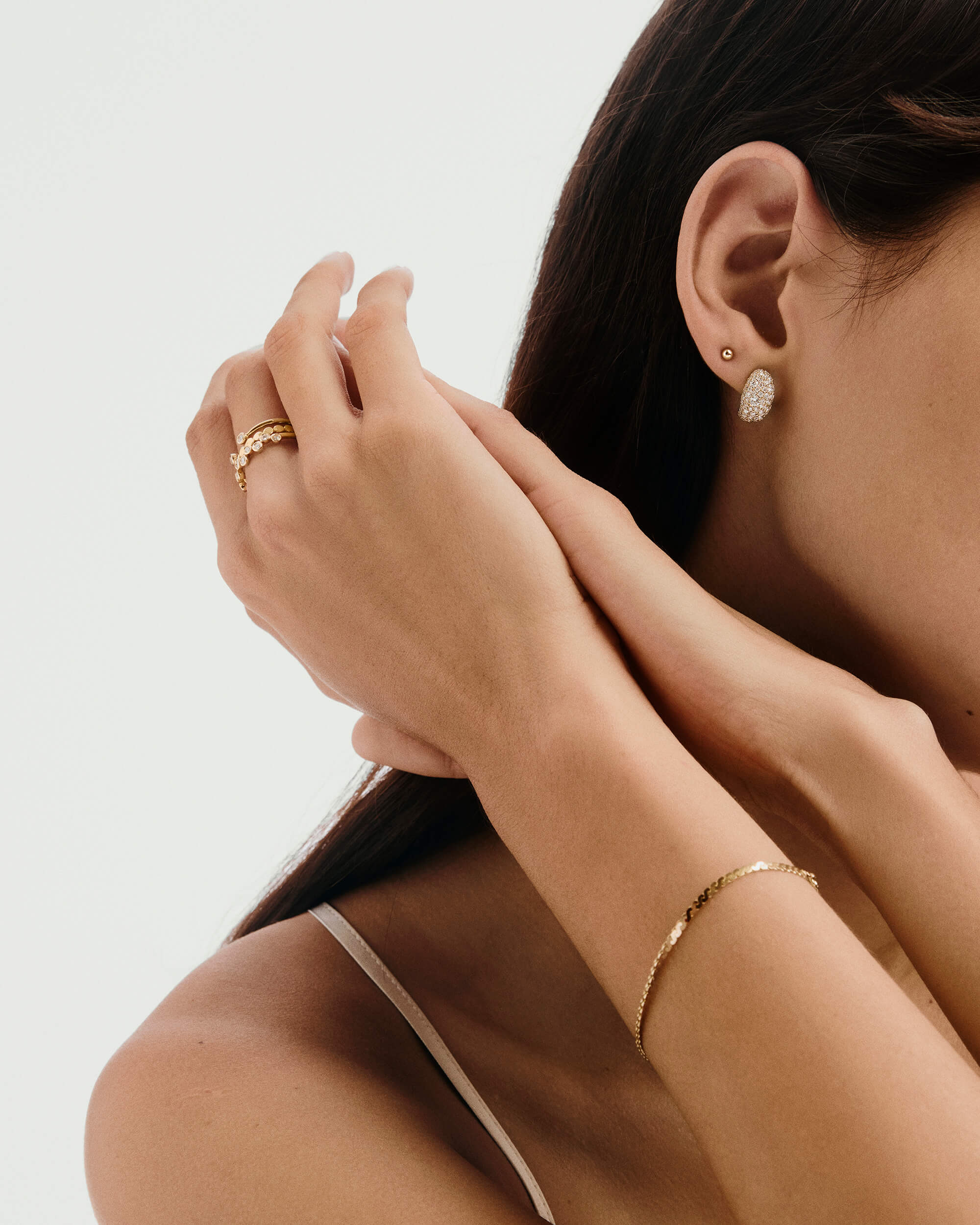DÃ´me PavÃ© Lab Grown Diamond Huggies on a woman's ear, showcasing the cobblestone setting with densely packed, varied-sized lab-grown diamonds for a smooth shine.