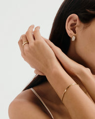 DÃ´me PavÃ© Lab Grown Diamond Huggies on a woman's ear, showcasing the cobblestone setting with densely packed, varied-sized lab-grown diamonds for a smooth shine.