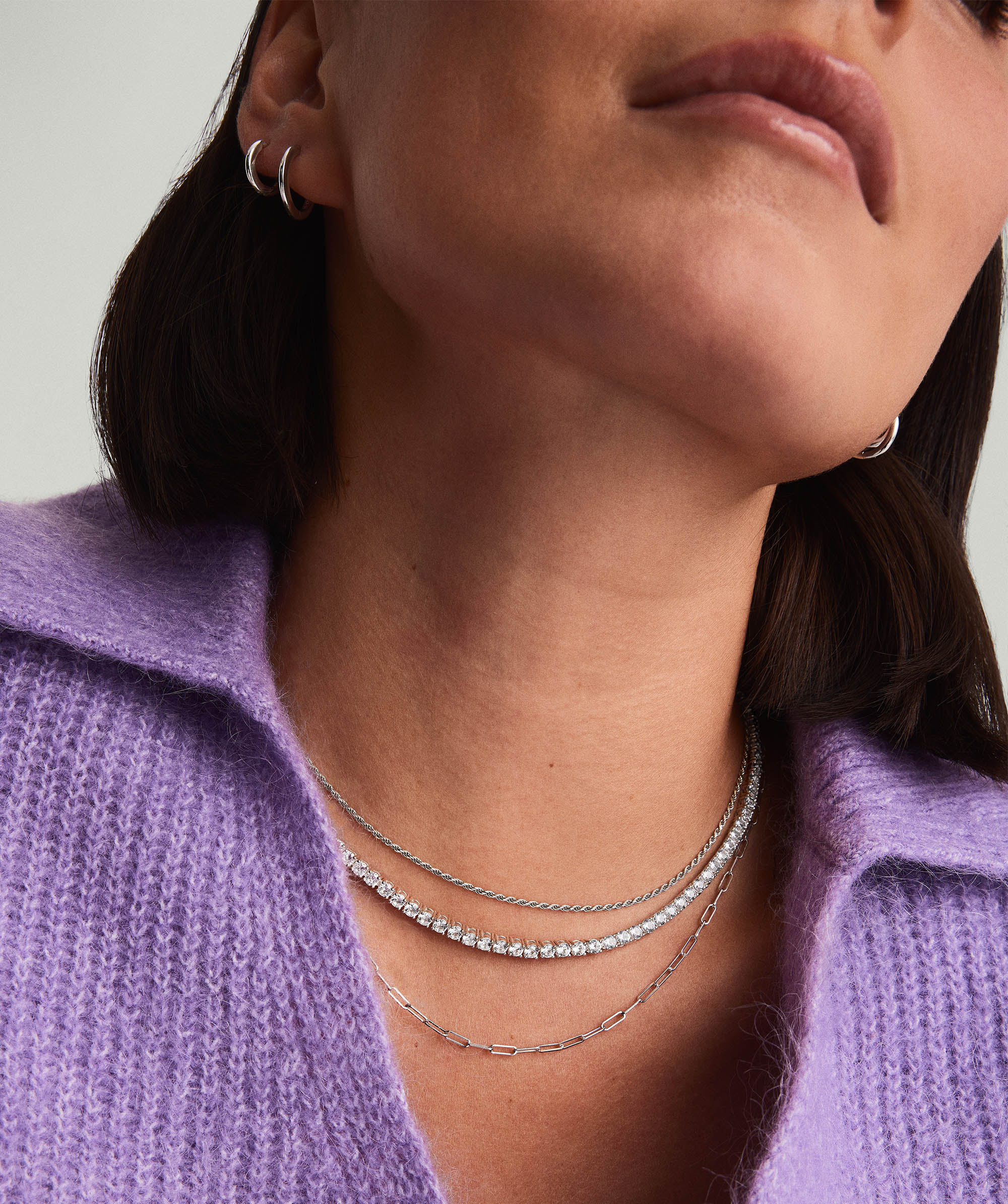 Woman wearing Lab Grown Sapphire Tennis Necklace crafted in sterling silver, with a close-up highlighting the necklace and matching silver hoop earrings.
