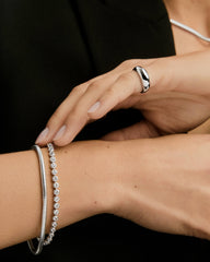 Zadie Bezel Lab Grown Sapphire Tennis Bracelet elegantly adorns a woman's wrist, showcasing its bezel-set sapphires, capturing the essence of sophisticated jewelry design.