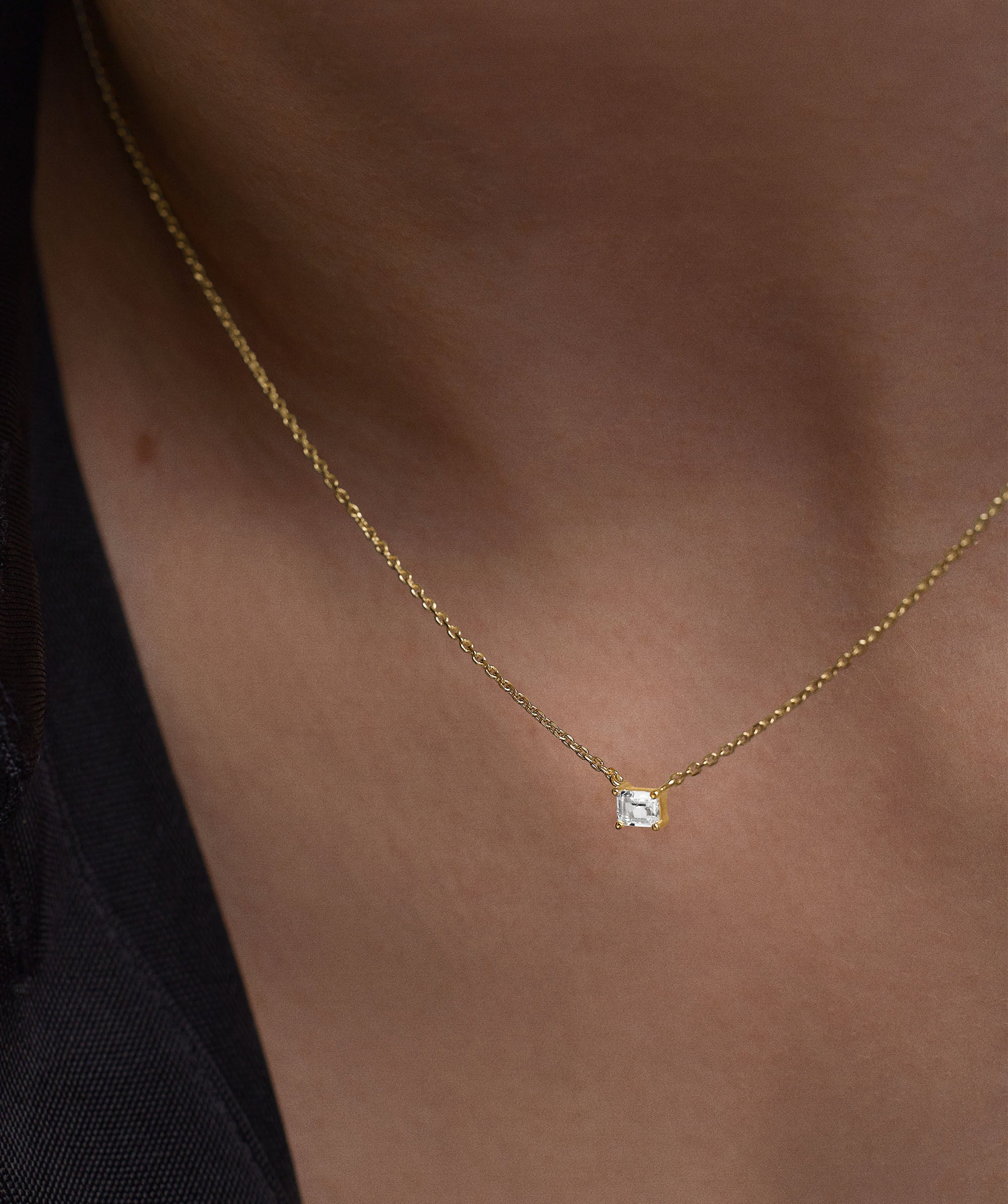 Person wearing Lab Grown Sapphire Baguette Necklace, featuring an emerald cut sapphire pendant on a gold chain, highlighting its elegant design for everyday wear.