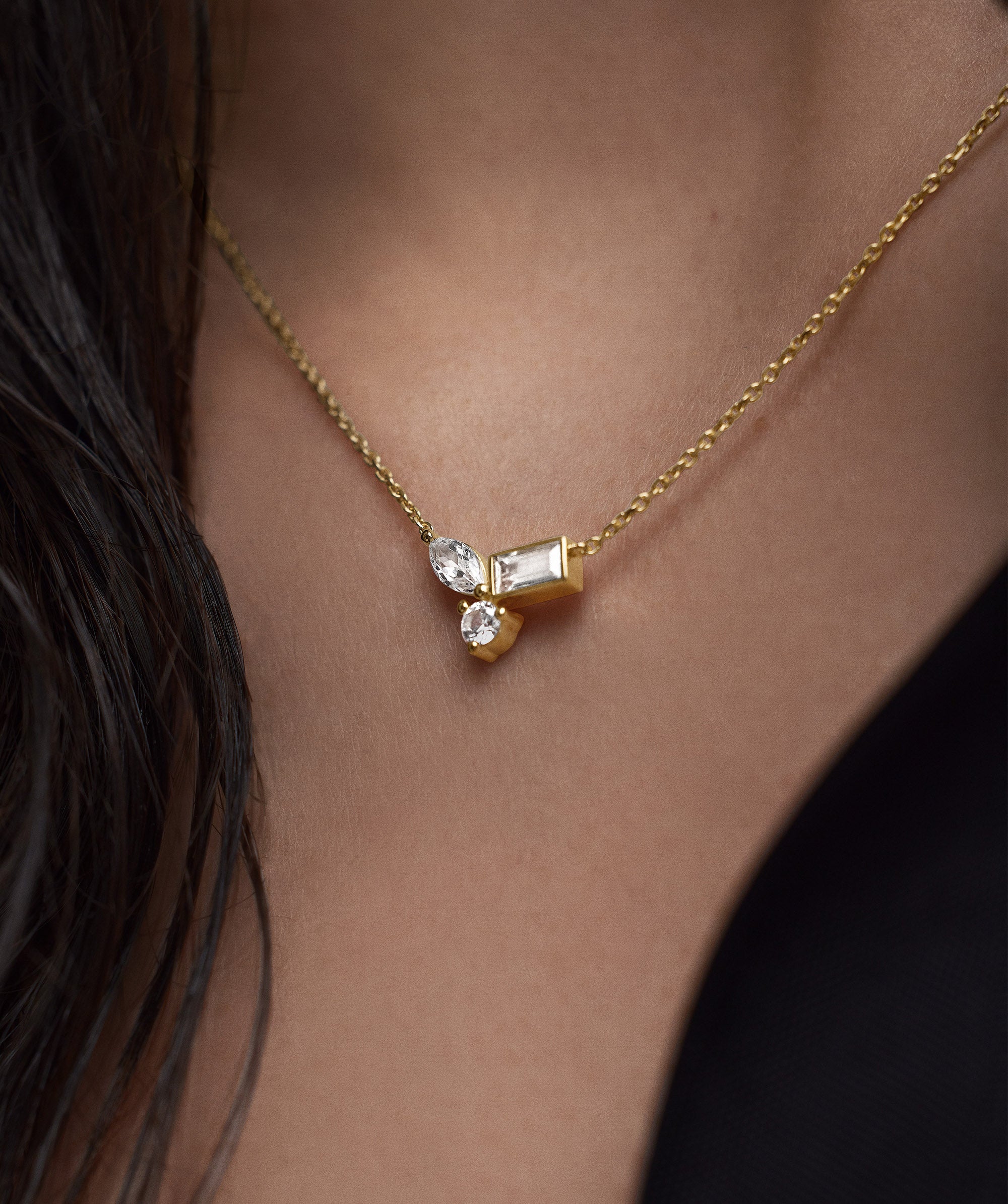 Woman wearing the Lab Grown Sapphire Cluster Necklace, featuring marquise, emerald, and round cut sapphires in a stylish, classic design.