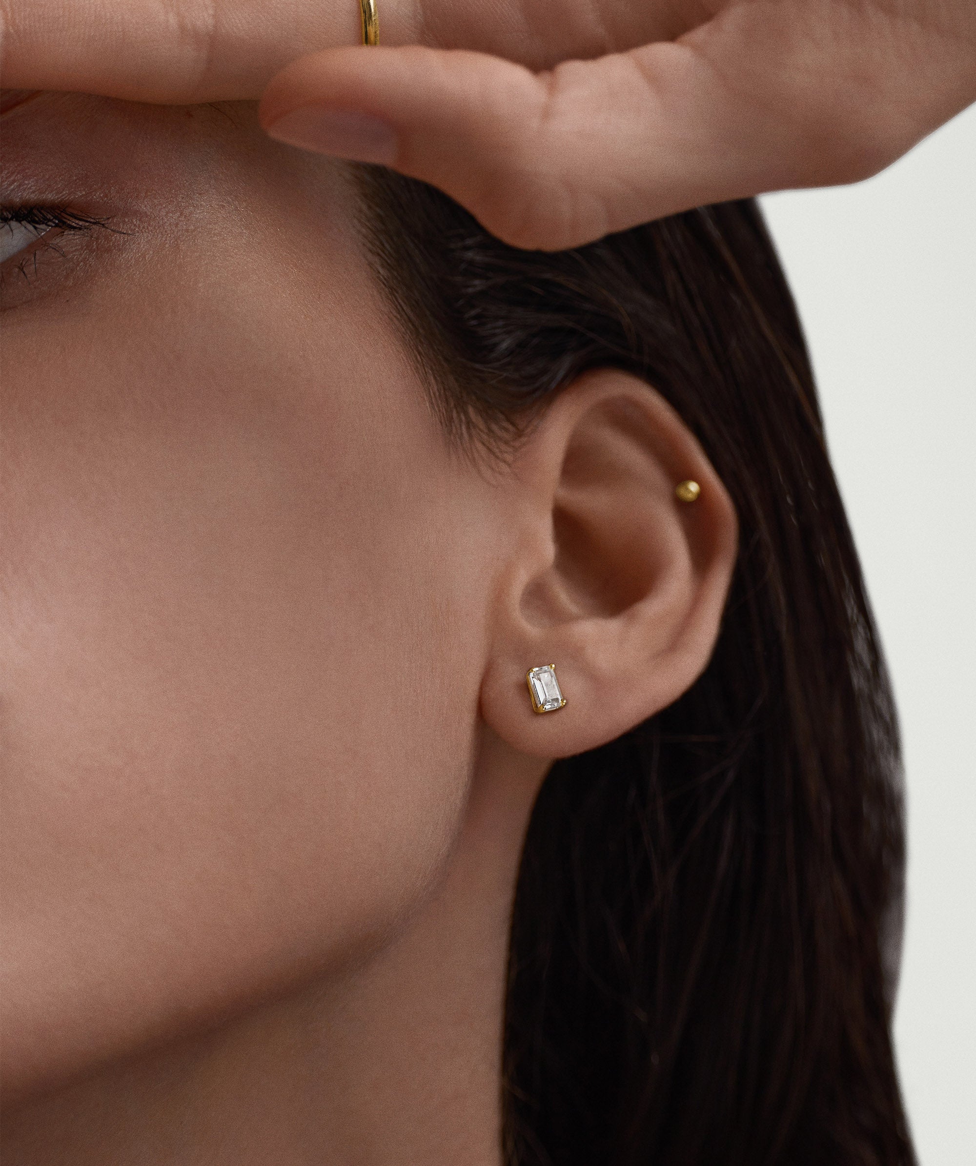 Close-up of a woman's ear wearing a Lab Grown Sapphire Emerald Cut Stud earring, showcasing the elegant and classic design.