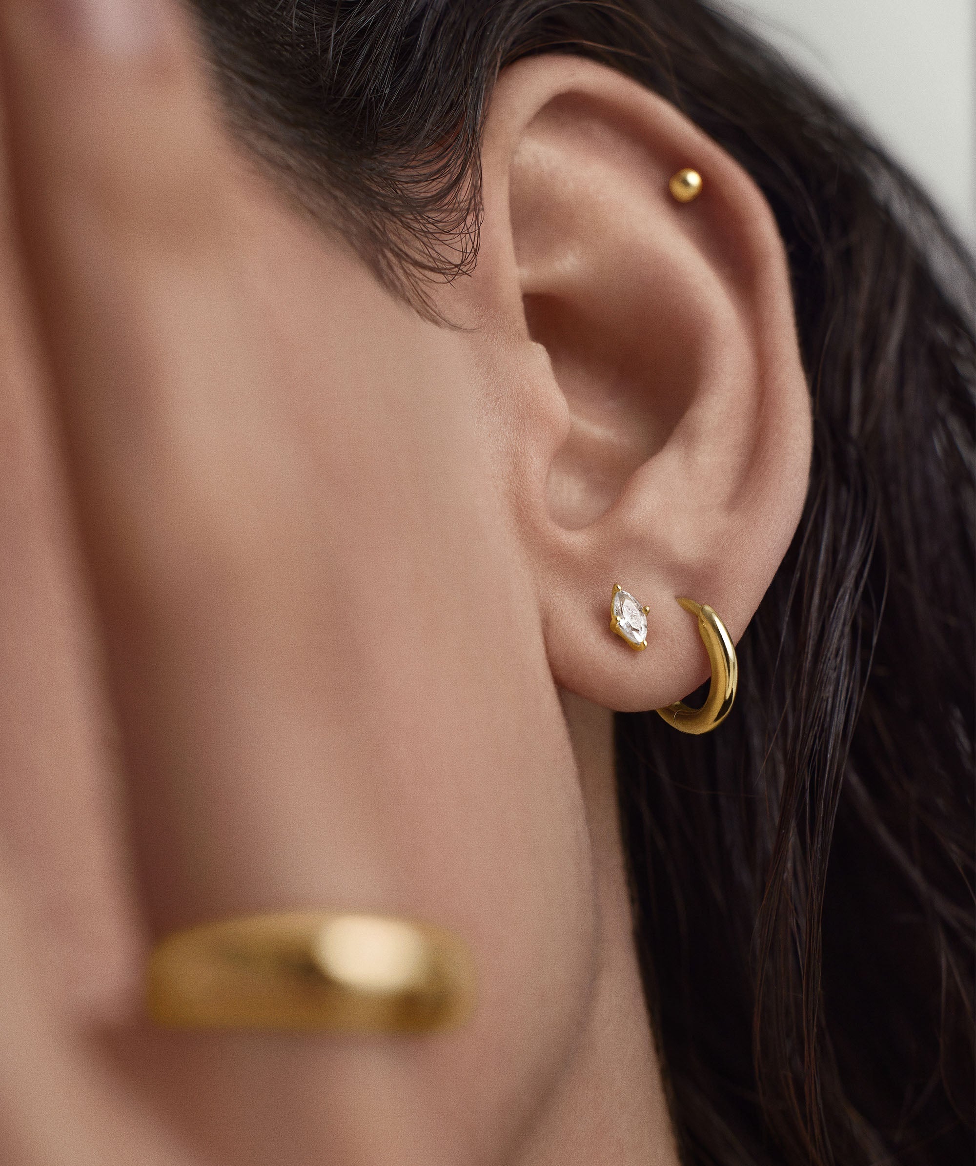 Close-up of a woman's ear wearing Lab Grown Sapphire Marquise Cut Studs, showcasing the elegant stud earring style inspired by French Royal Court fashion.