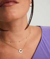 Woman wearing the Linked PavÃ© Diamond Pearl Necklace featuring two interlinked rings in 14k gold with responsibly sourced diamonds and mother of pearl.