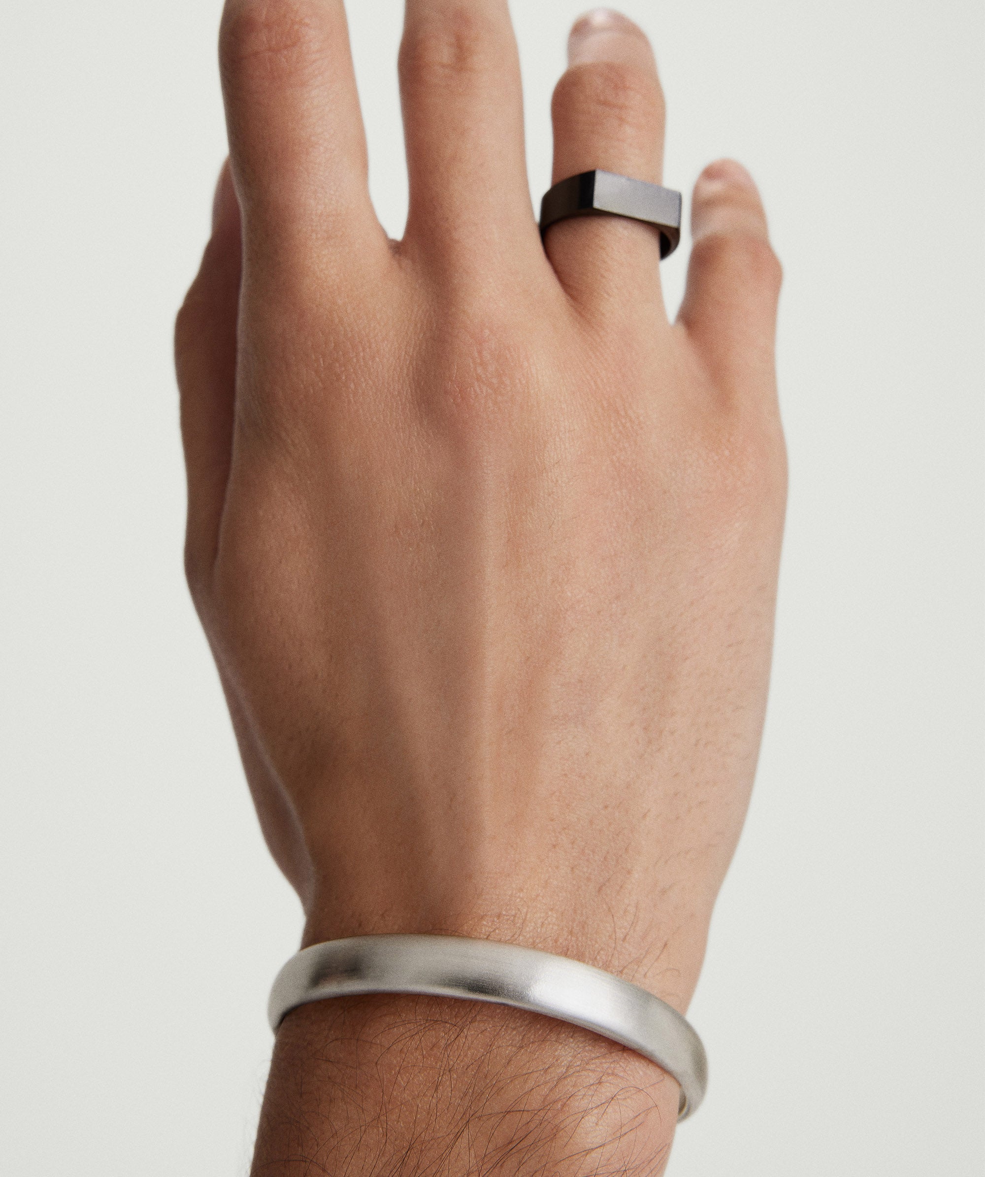 Hand wearing a Bold Cuff bracelet and a ring, showcasing the simple yet bold silhouette of the fashion accessory.