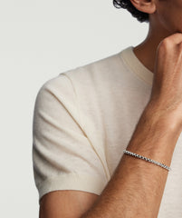 Person wearing a light-cream T-shirt with a 4mm Round Box Chain Bracelet on their wrist, showcasing the bracelet's simplicity and handcrafted sterling silver design.