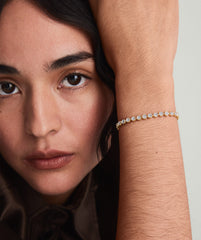Woman wearing the Micro-PavÃ© Diamond RiviÃ¨re Bracelet, showcasing its continuous stream of knife edge bezel set diamonds on her wrist.