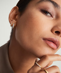 Close-up of a woman's face wearing Bold PavÃ© Diamond Small Hoops, handcrafted in 14k solid gold with responsibly sourced diamonds, highlighting their elegant sparkle.