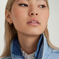 Close-up of a woman wearing Tube Medium Hoops with a clicker closure, showcasing their bold and modern design.