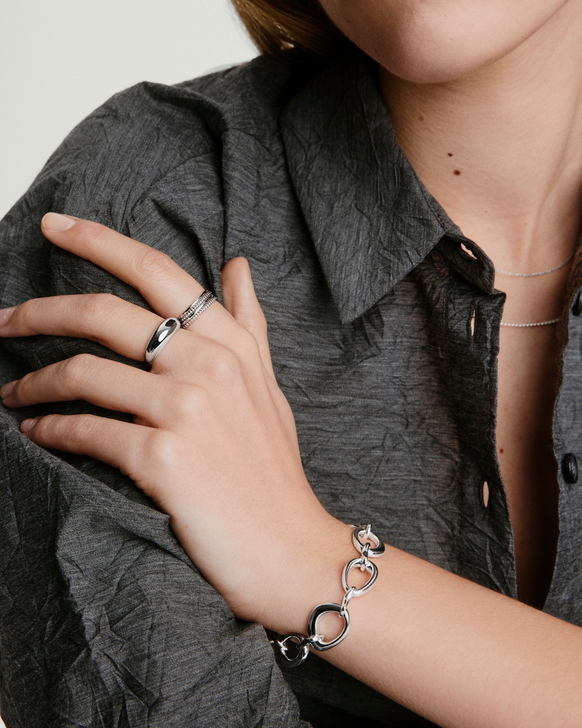 Woman wearing the Organic DÃ´me Ripple Chain Bracelet, showcasing its open, organic design linked with a toggle clasp, emphasizing its stylish, wearable appeal.