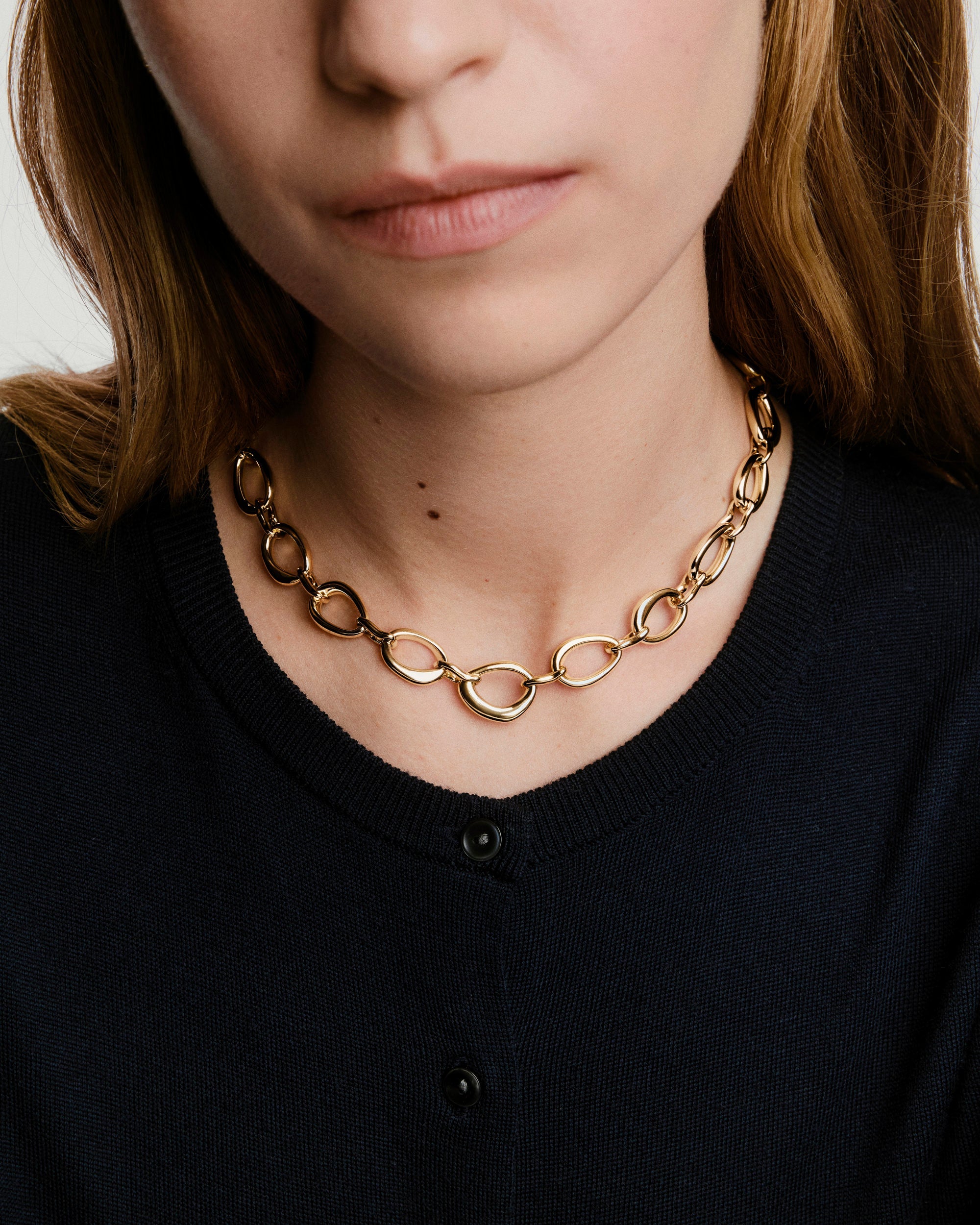 A woman wears the Organic DÃ´me Ripple Chain Necklace featuring organic, irregular links and a toggle clasp, highlighting its elegant, fluid design on her neck.
