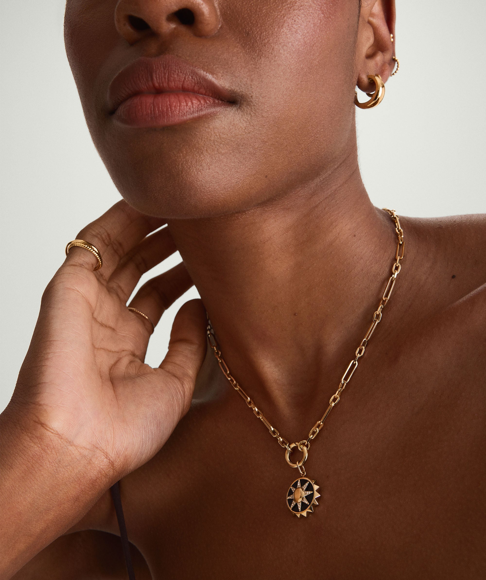 Close-up of a woman's neck wearing a handcrafted 14k gold Triple Link Paperclip Chain Charm Necklace.