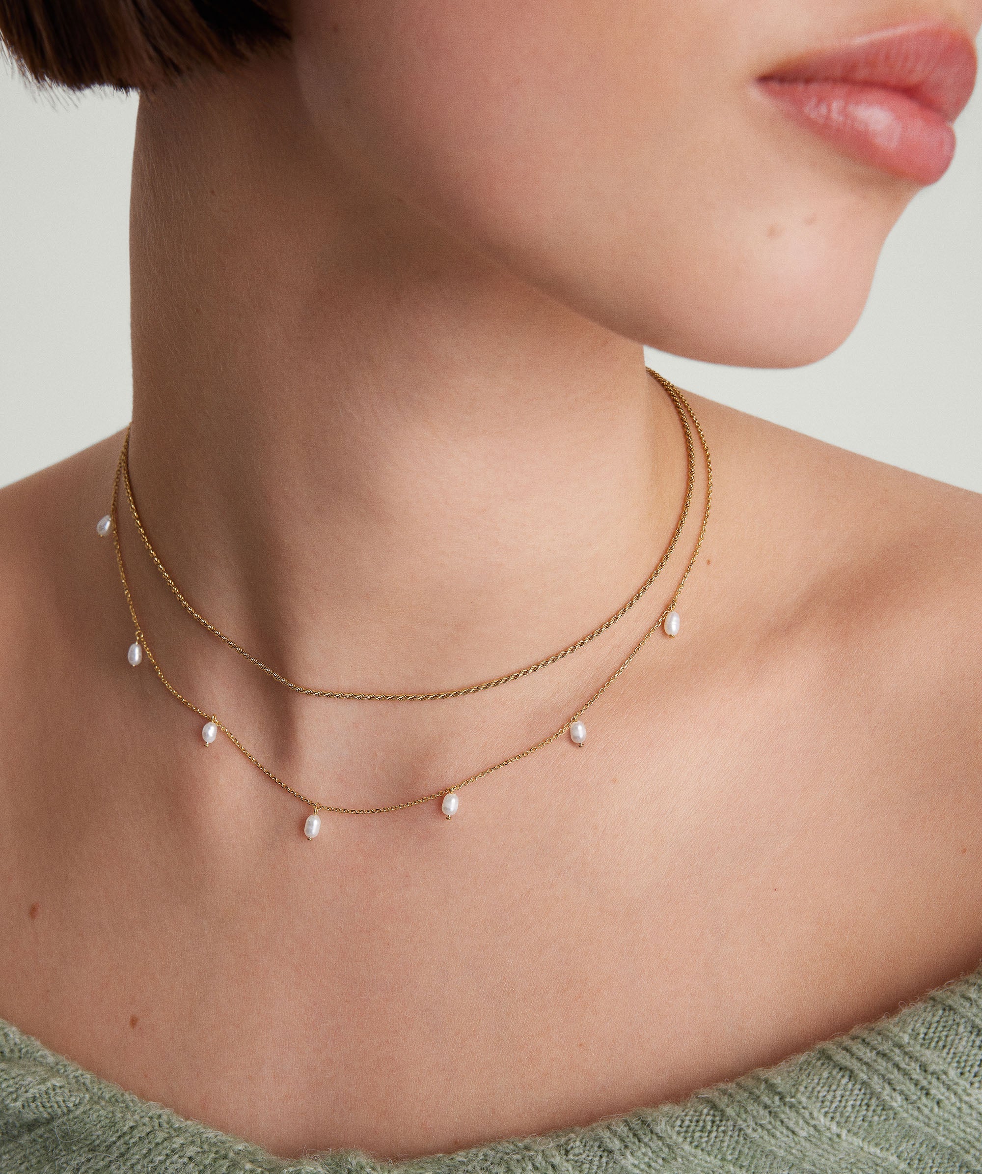 Woman wearing the Tiny Pearl Station Necklace, handcrafted in 18k gold vermeil with freshwater pearls, highlighting its delicate and elegant design around her neck.