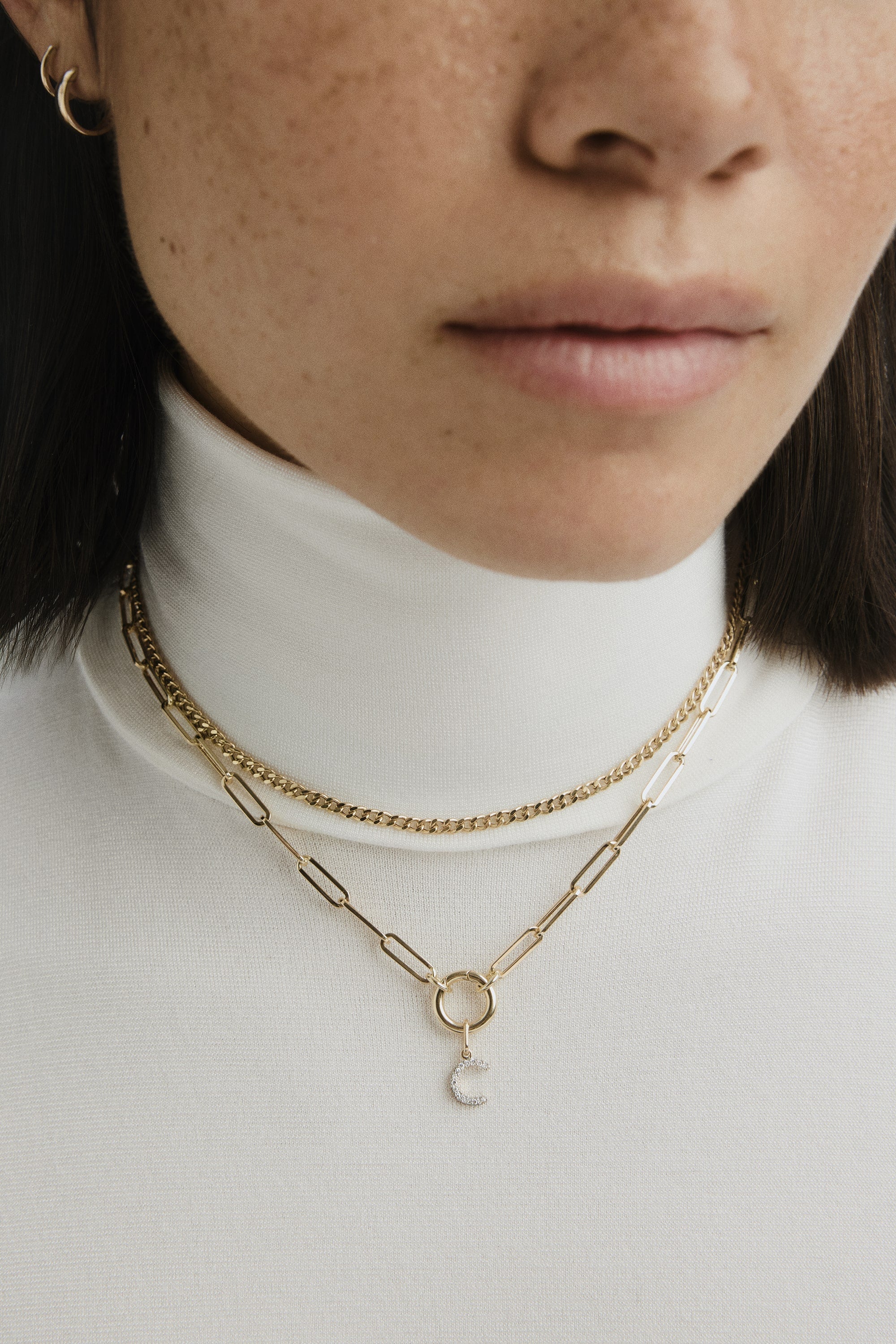 Close-up of a woman's neck wearing the Paperclip Chain Charm Necklace, featuring a bold chain and stacker clasp for layering charms. Handcrafted in 14k recycled solid gold.