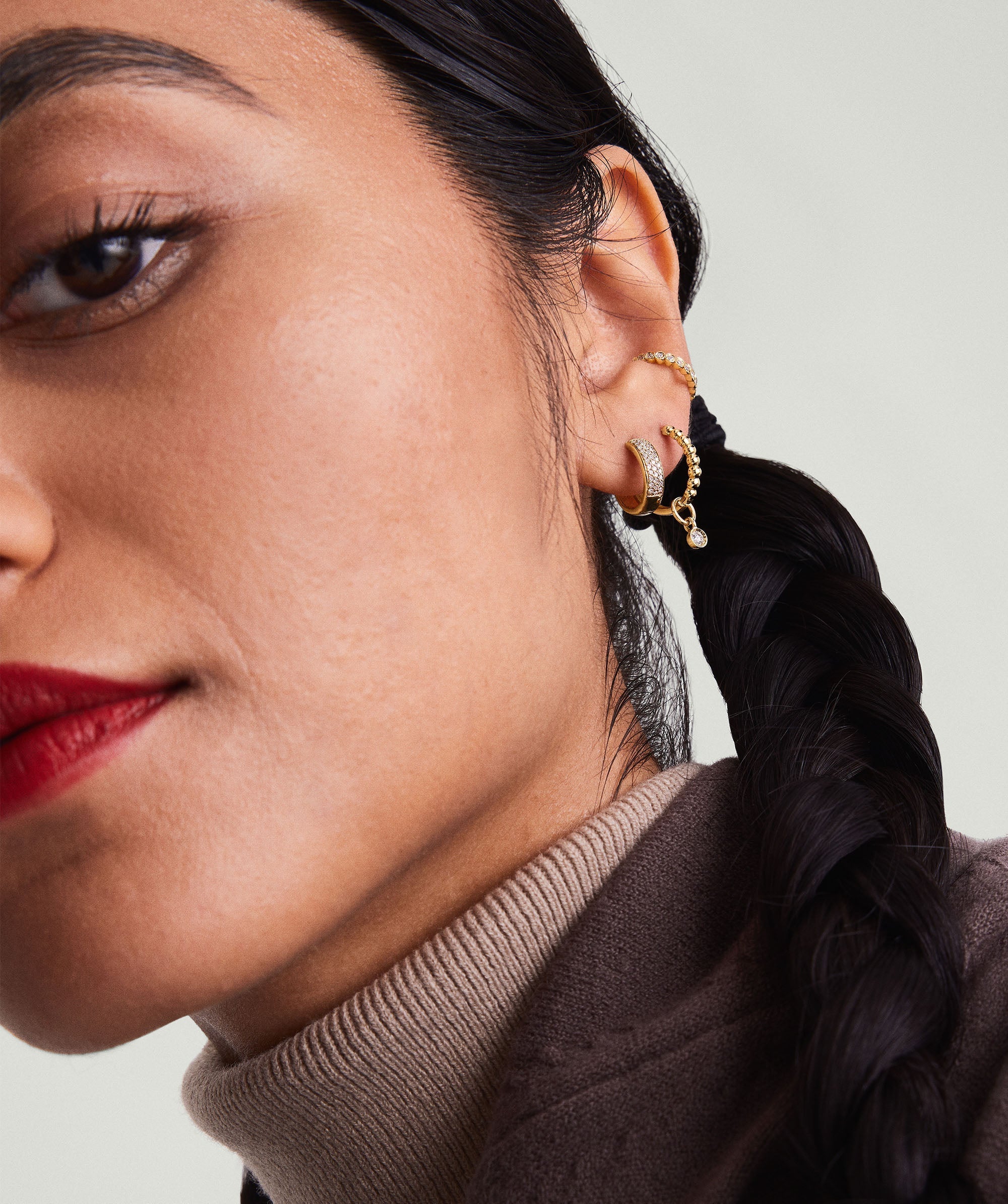Close-up of a woman's face showcasing Bold PavÃ© Diamond Huggie Hoops in 14k solid gold, adorned with responsibly sourced diamonds.