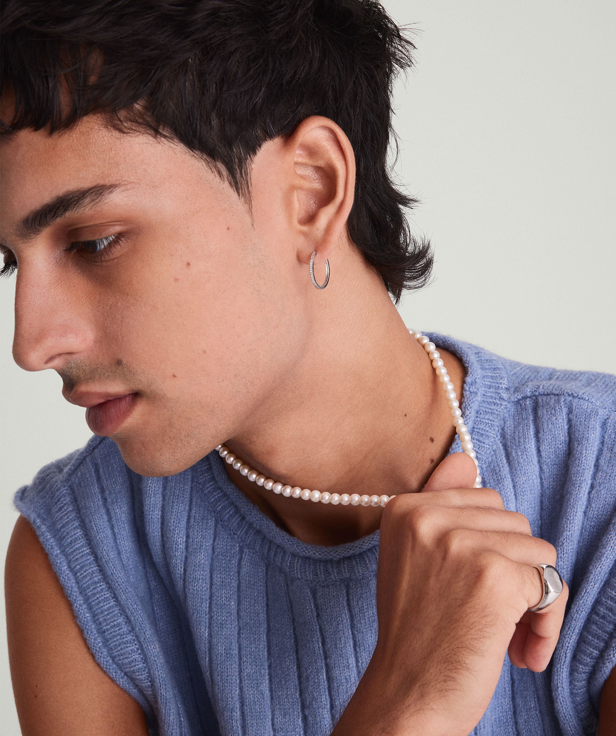 Paradigm Pearl Necklace: A man wears a blue sweater and a handcrafted freshwater pearl necklace with a sterling silver clasp.