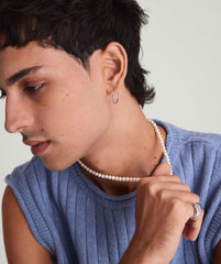 Paradigm Pearl Necklace: A man wears a blue sweater and a handcrafted freshwater pearl necklace with a sterling silver clasp.