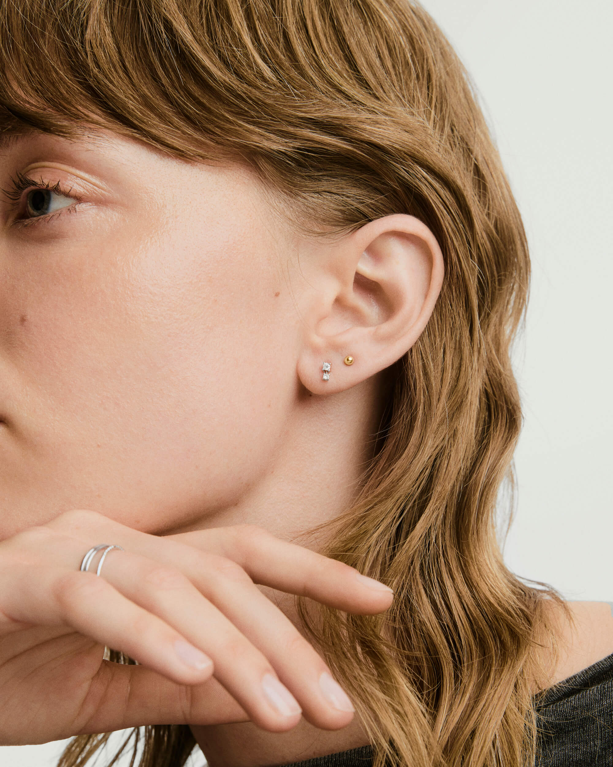 Close-up of a woman's ear adorned with the Piercing Studio - Diamond Droplet Stud, highlighting the elegant design and subtle sparkle.