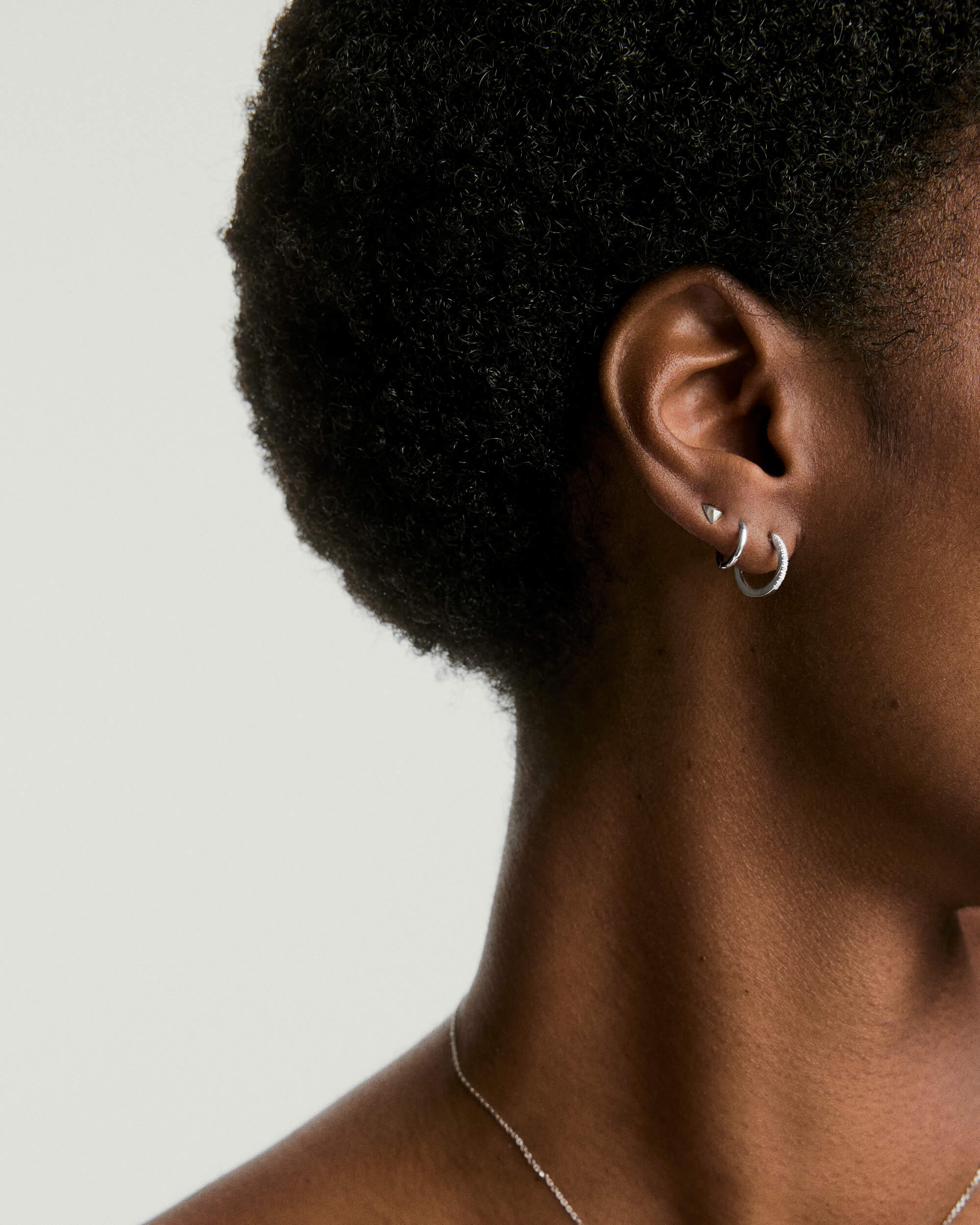 Close-up of a woman's ear adorned with a Piercing Studio - Puffy Pyramid Flat Back Stud, highlighting the intricate design and fashionable accessory appeal.
