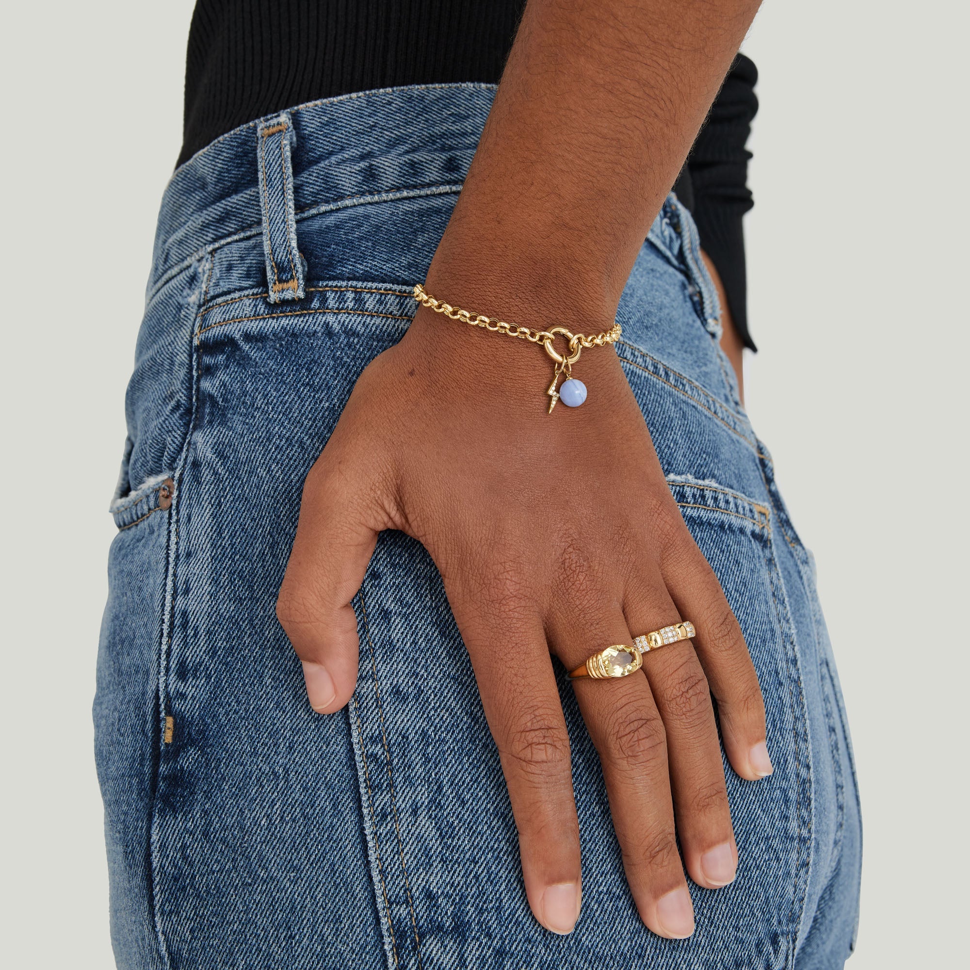 Rolo Chain Charm Bracelet on a hand, featuring a 14k gold chain with a Stacker Clasp, shown against blue denim.