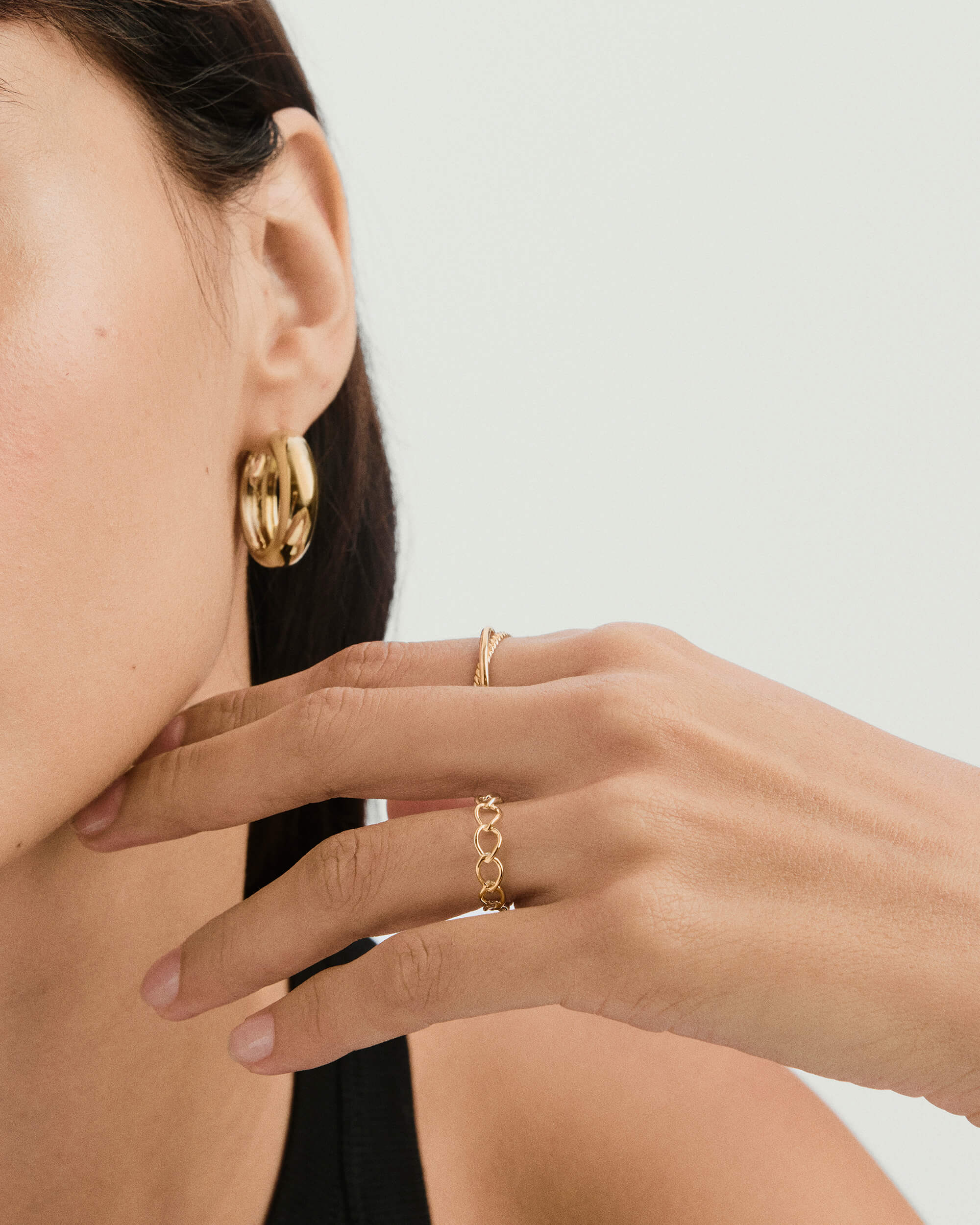 Close-up of a woman's hand wearing a braided ring, showcasing its chain-style design, symbolizing unity and strength.