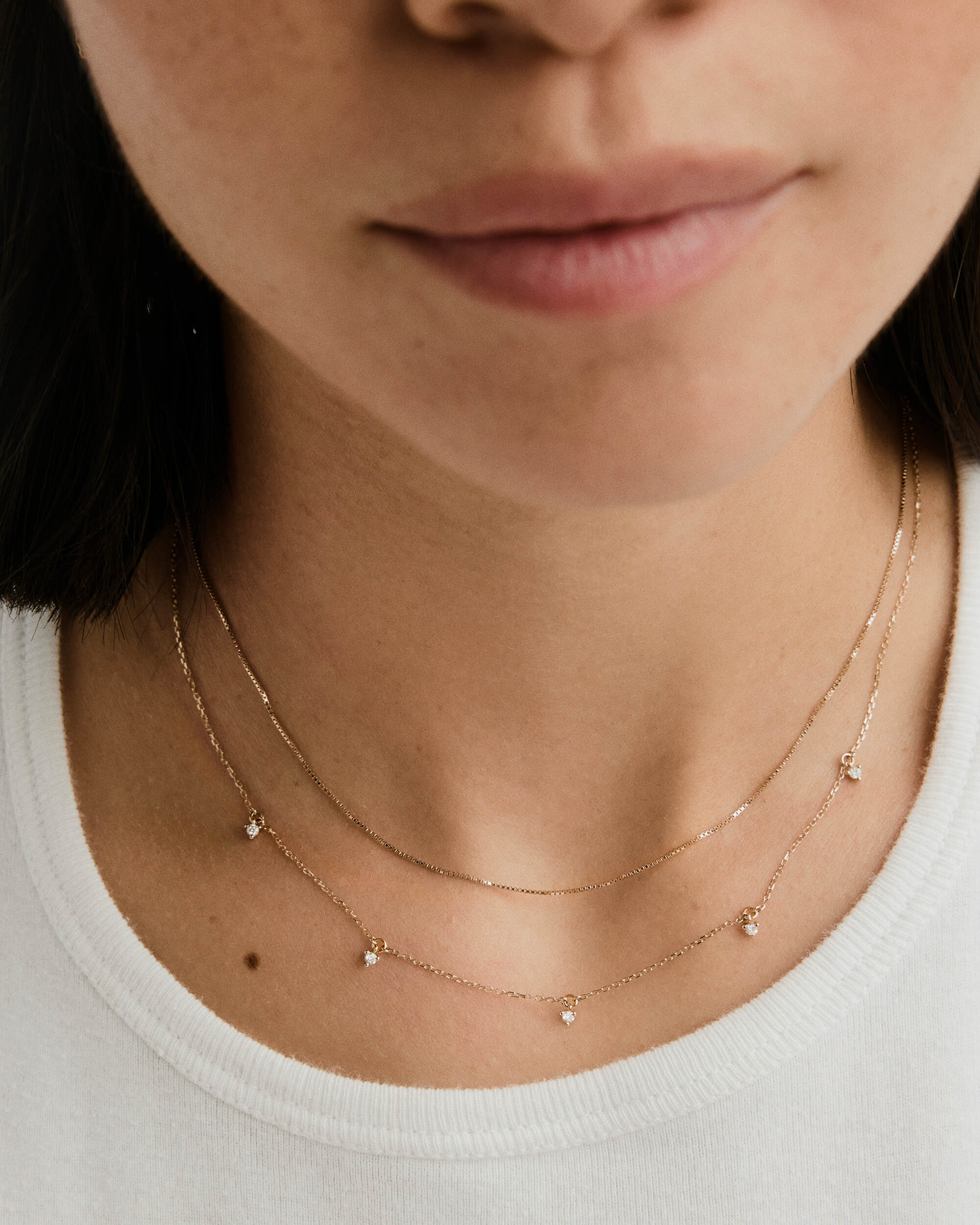 Woman wearing the Multi Station Diamond Necklace, a handcrafted 14k gold choker with five responsibly sourced diamonds, elegantly positioned on her neck.