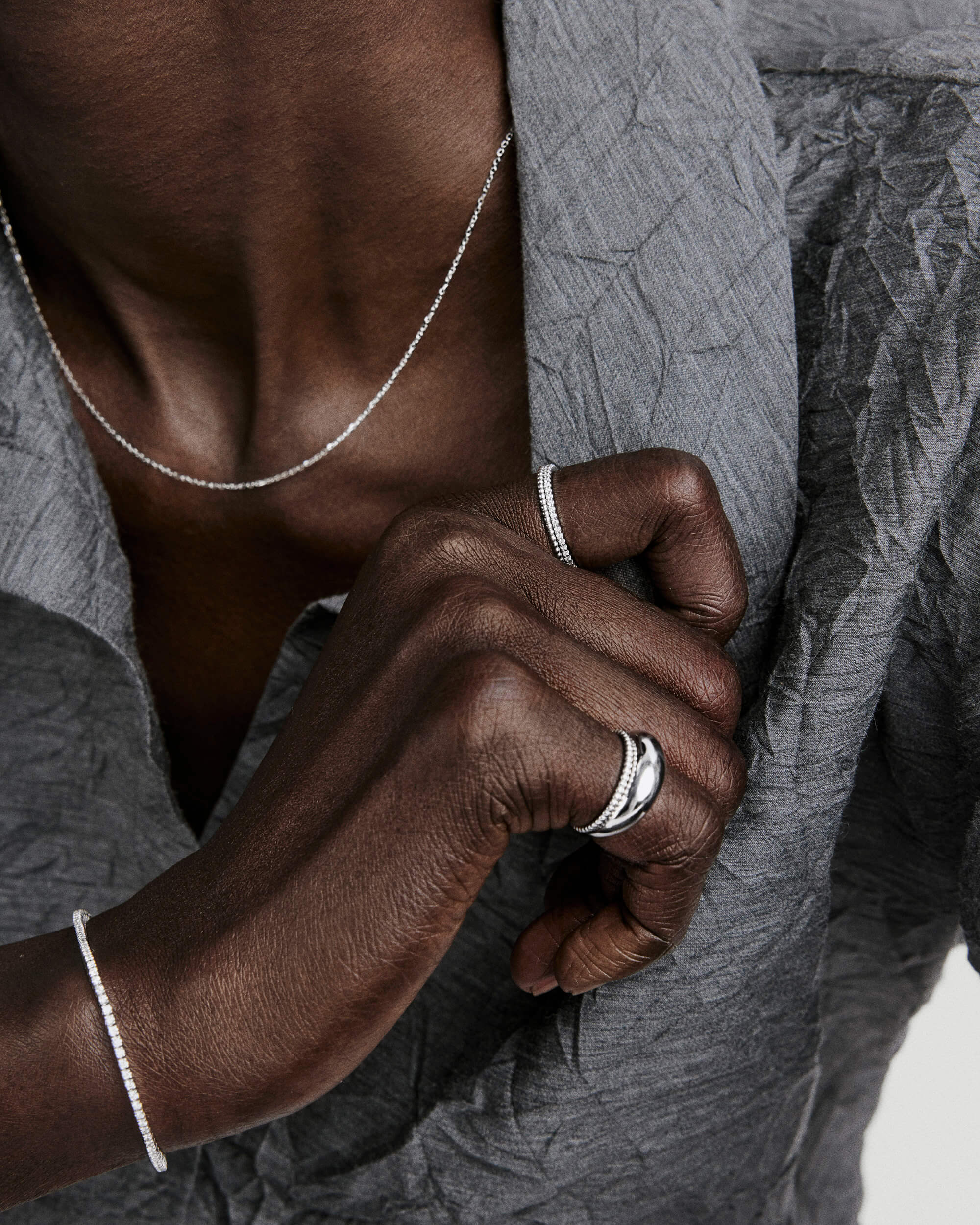 A close-up showcases a Beaded Ring on a hand, featuring a polished, domed band in 14k white gold with rhodium plating, among other silver jewelry.