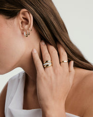 PavÃ© Diamond Huggie Hoops on a woman's ear, showcasing handcrafted 14k gold with pavÃ© diamonds, designed for versatile wear.