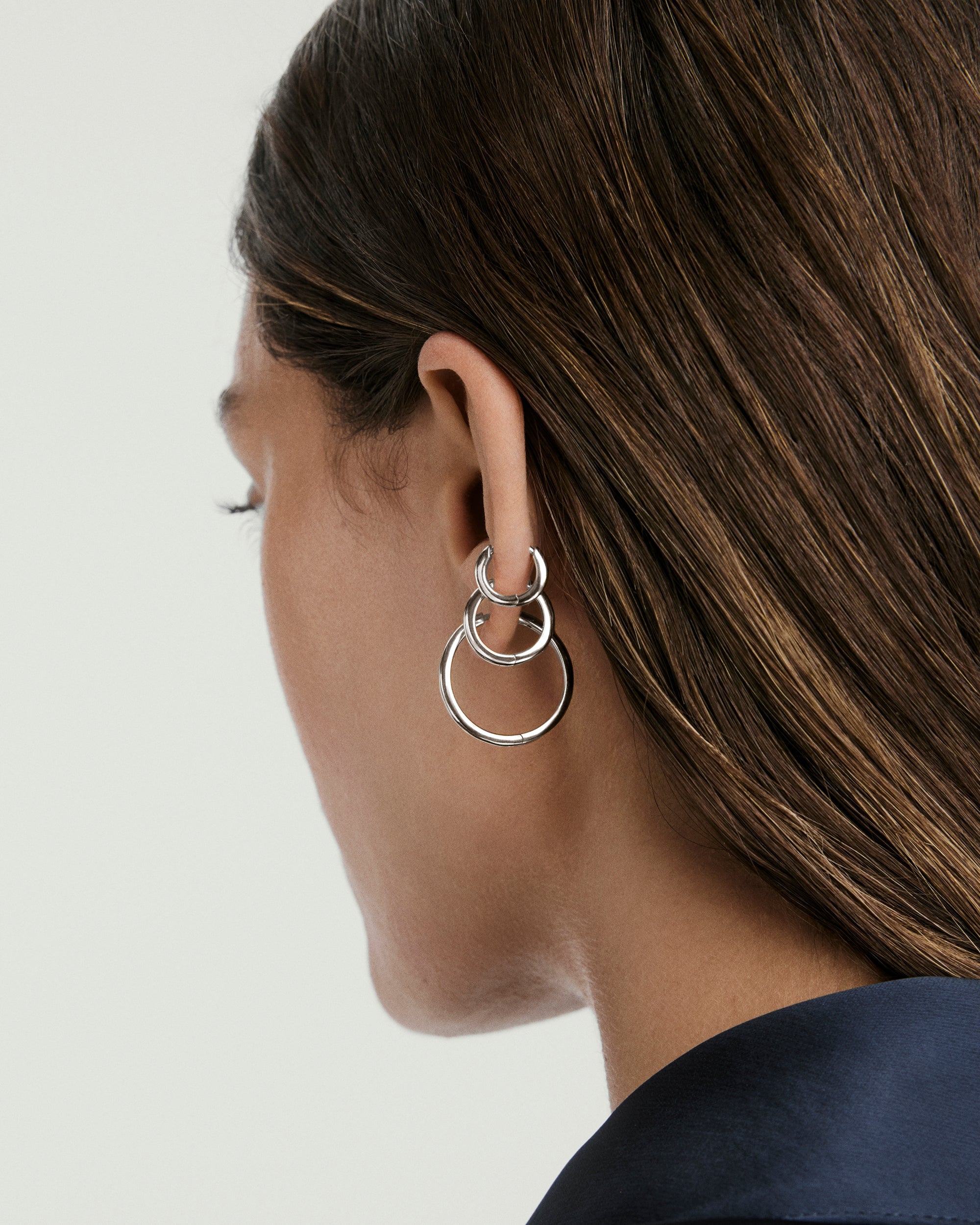 Woman wearing the Tube Hoops Bundle, showcasing Huggie, Medium, and Large Tube Hoops. Fine jewelry, perfect for stacking and enhancing any look.