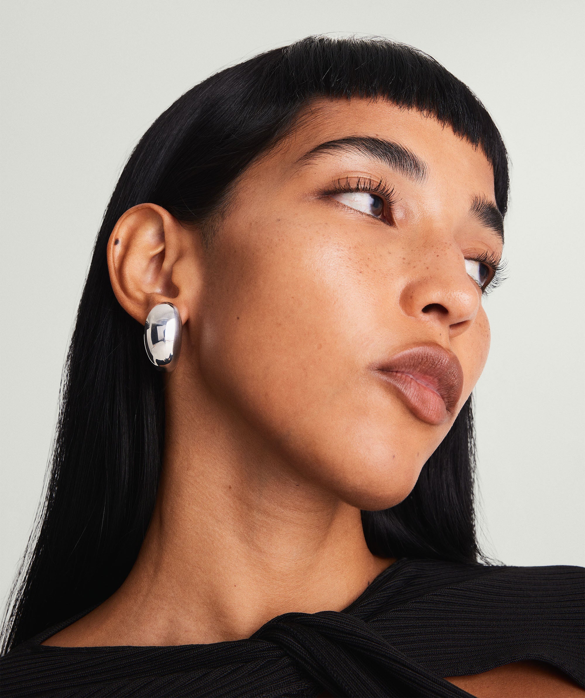 Woman wearing Mega DÃ´me Earrings, looking to the side. The earrings are a bold, standout piece from the DÃ´me collection, emphasizing elegance and attention-commanding style.