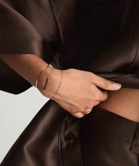 Close-up of a woman's hand wearing the Serpentine Chain Bracelet featuring flat, braided links, highlighting its sleek and comfortable design.