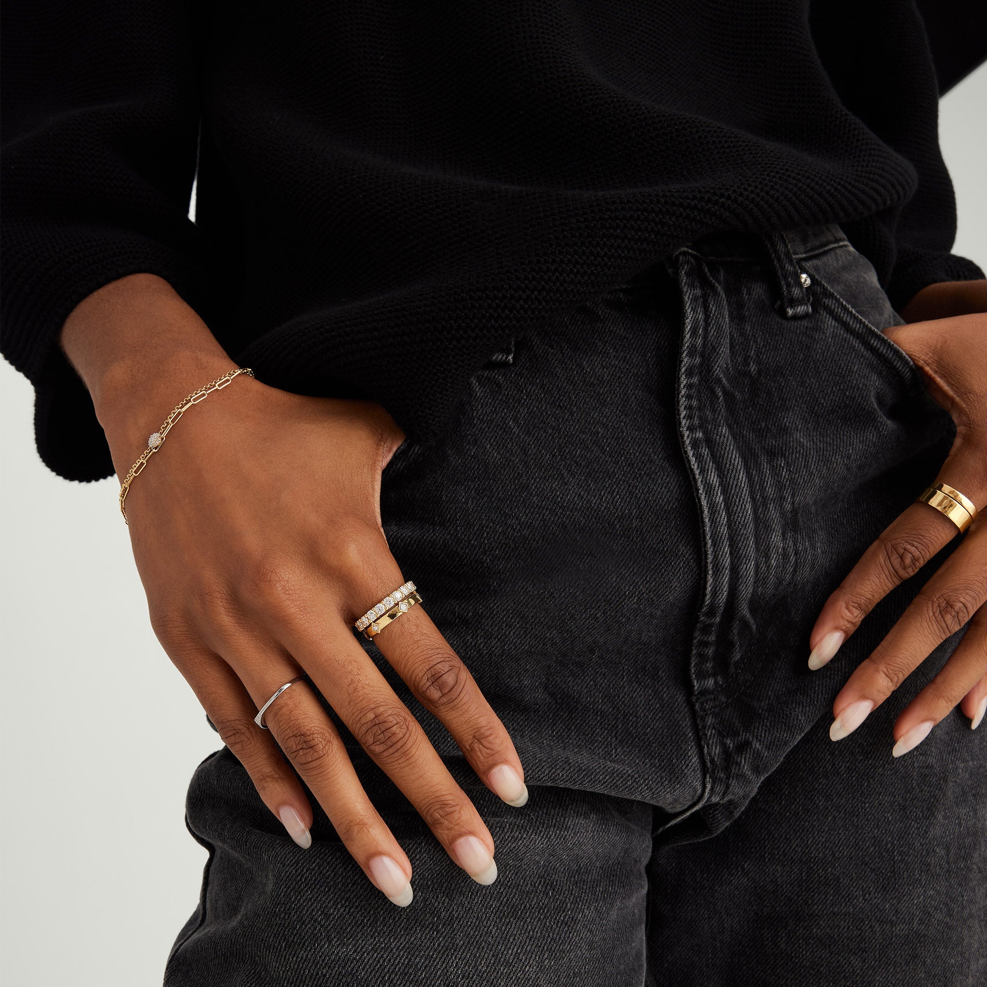 Person wearing the 3mm Bold Diamond Eternity Band with 14k gold and 22 round brilliant cut diamonds, along with other rings and bracelets.