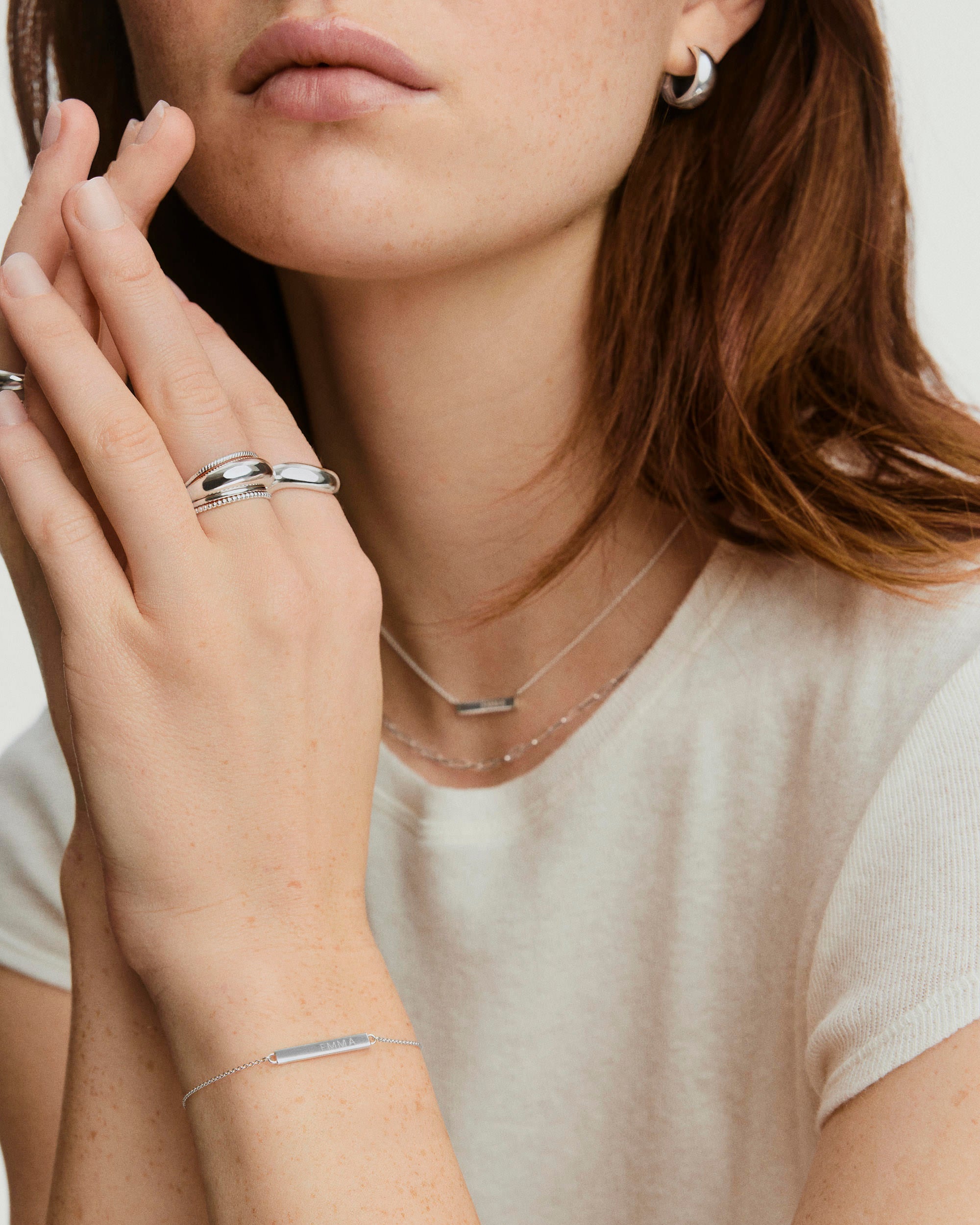 Engravable Bar Bracelet showcased on a woman's wrist, paired with silver jewelry, highlighting its customizable design for personalized messages.