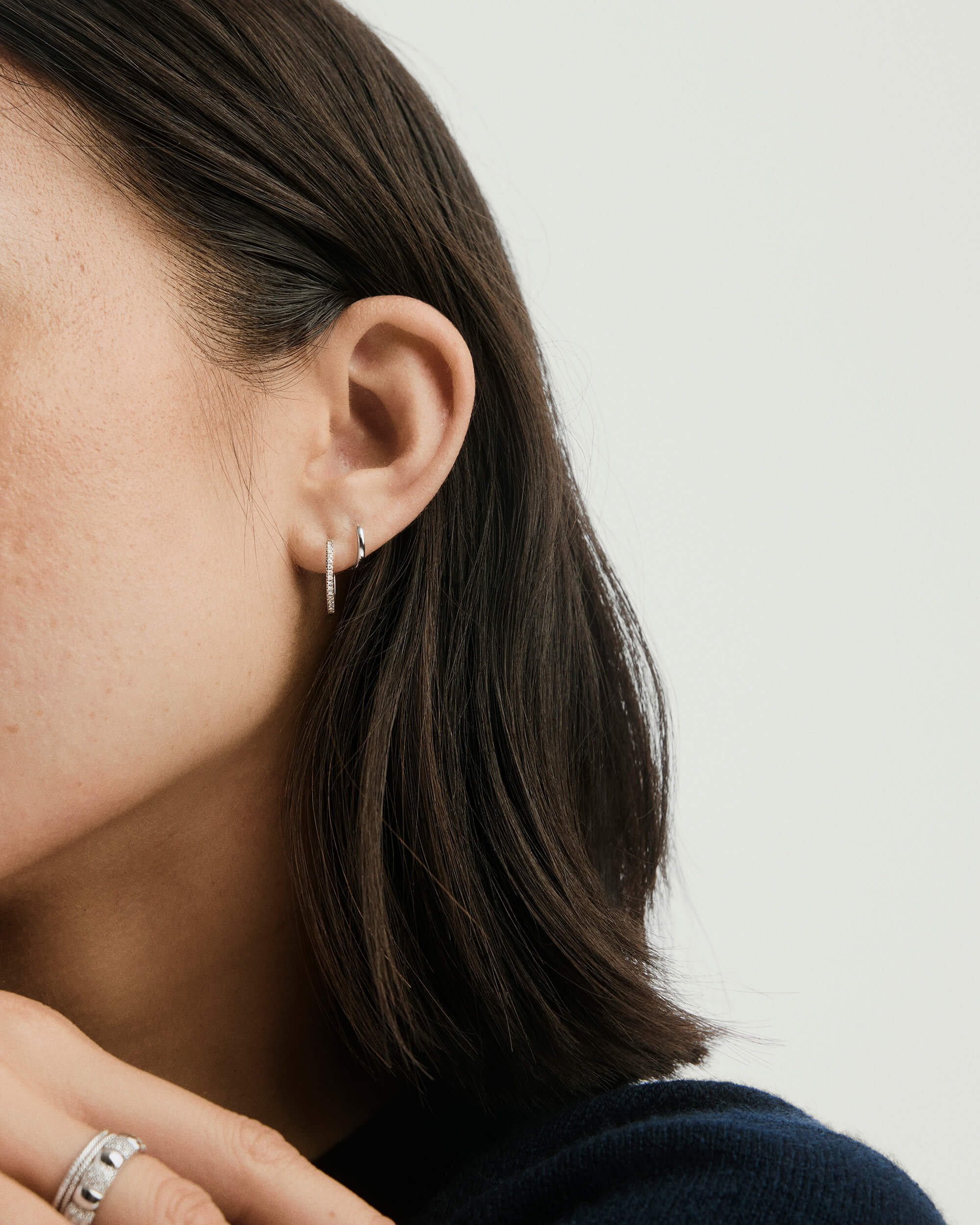 Close-up of a woman's ear showcasing the Mini Hoop earring. The lightweight hoop with a hinge clasp is ideal for everyday wear.