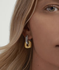 Close-up of a woman's ear wearing the Stevie Hoops and Links Mixed Metals Bundle, showcasing gold and silver hoops with interchangeable, reversible links.