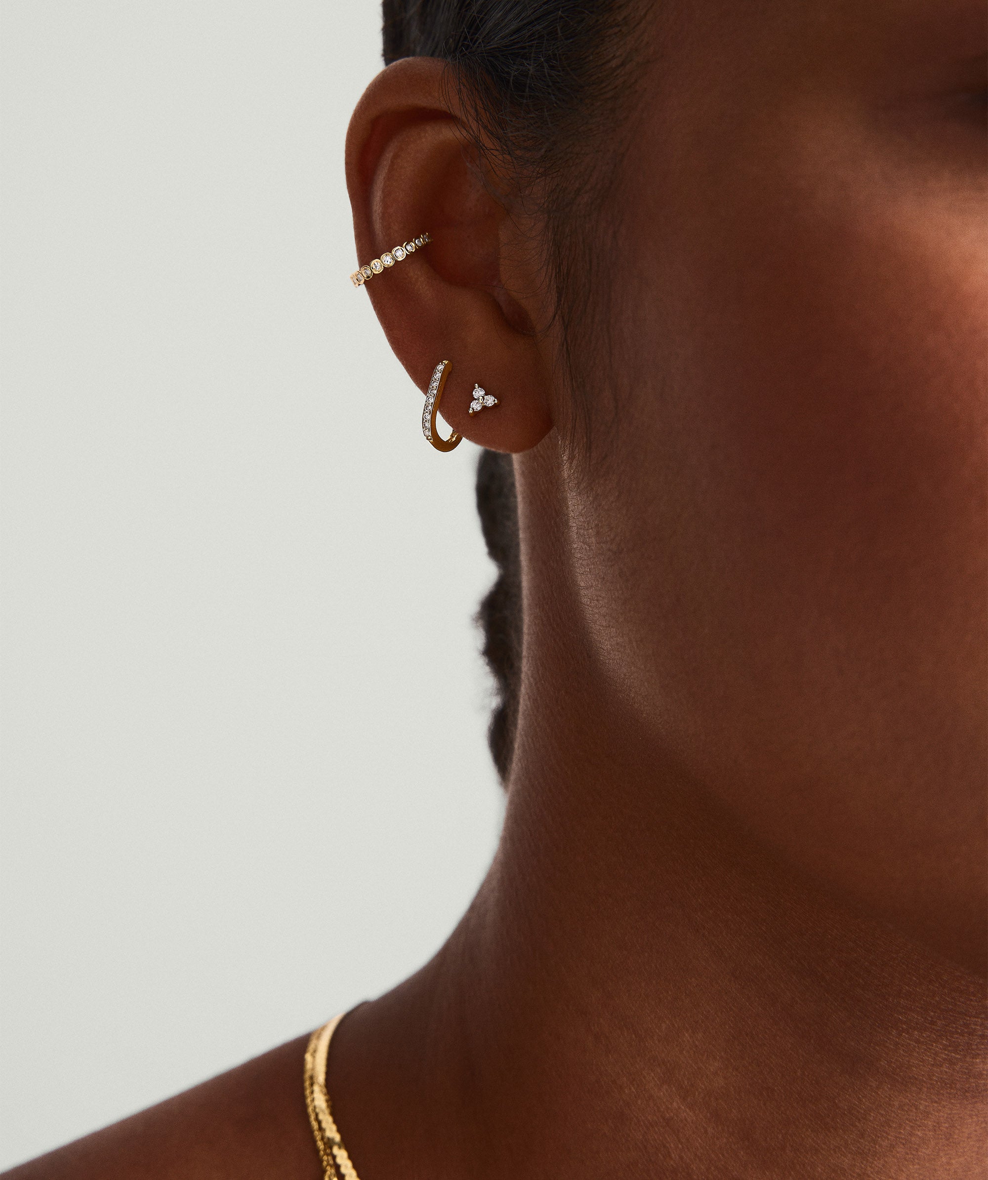 Close-up of a woman's ear adorned with Mini Lotus Diamond Studs, handcrafted in 14k gold with lotus-shaped, responsibly sourced diamonds.