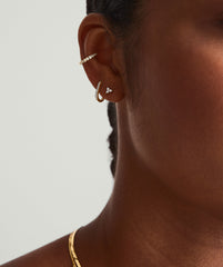 Close-up of a woman's ear showcasing a Mini Lotus Diamond Stud in 14k solid gold, featuring a lotus-shaped diamond, part of a fashion accessory collection.