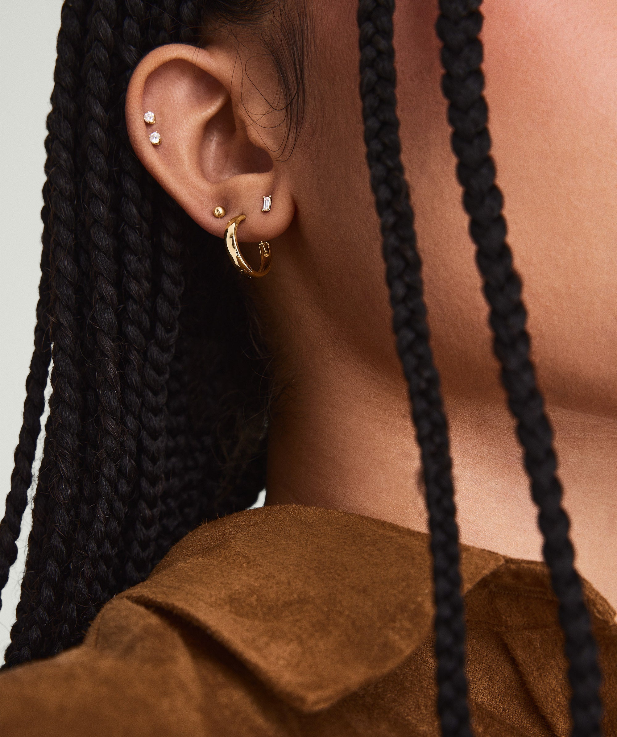 Mini Baguette Diamond Studs on a woman's ear, showcasing the handcrafted 14k solid gold setting and responsibly sourced baguette diamonds.