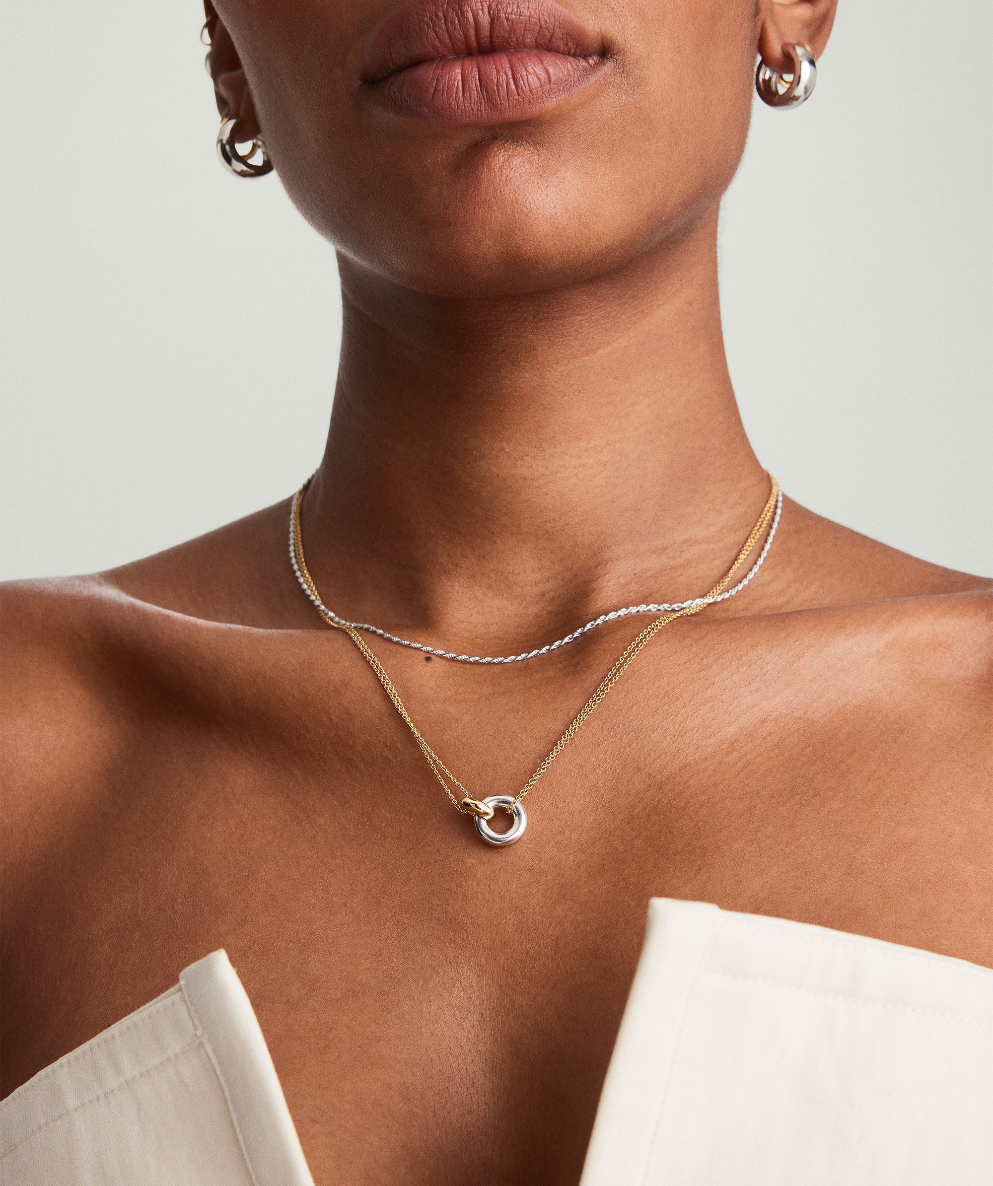 Woman wearing the Linked Two-Tone Necklace with interlinked rings, symbolizing personal bonds. The necklace is handcrafted in sterling silver and gold vermeil.