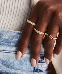 Wishbone Stacker Set on a hand, featuring gold rings elegantly displayed on fingers with close-up details of additional rings and a bracelet.