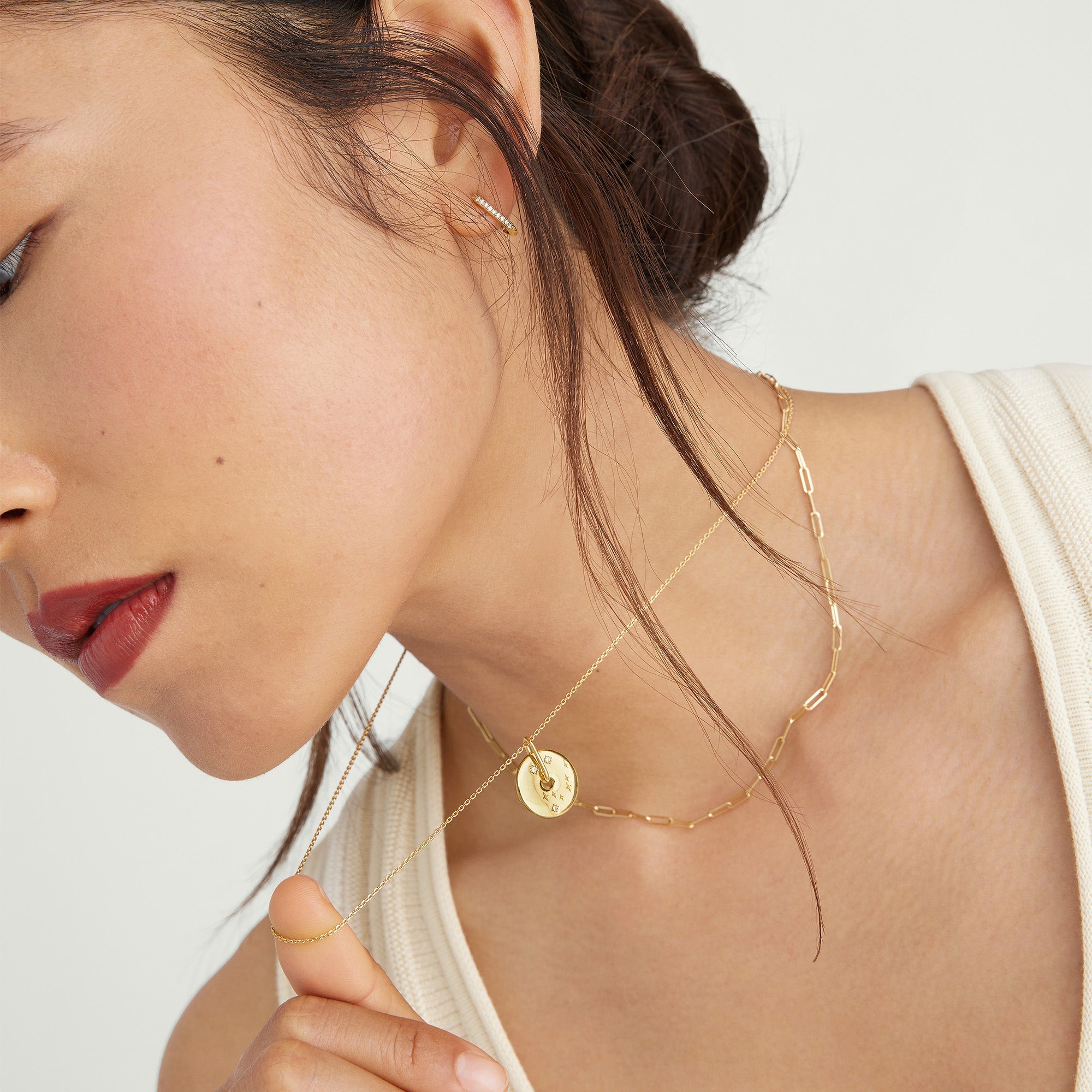 Zodiac Pendant Necklace: Woman wearing an 18k gold vermeil necklace with a spinning disk, featuring a constellation design set with white sapphire gemstones.