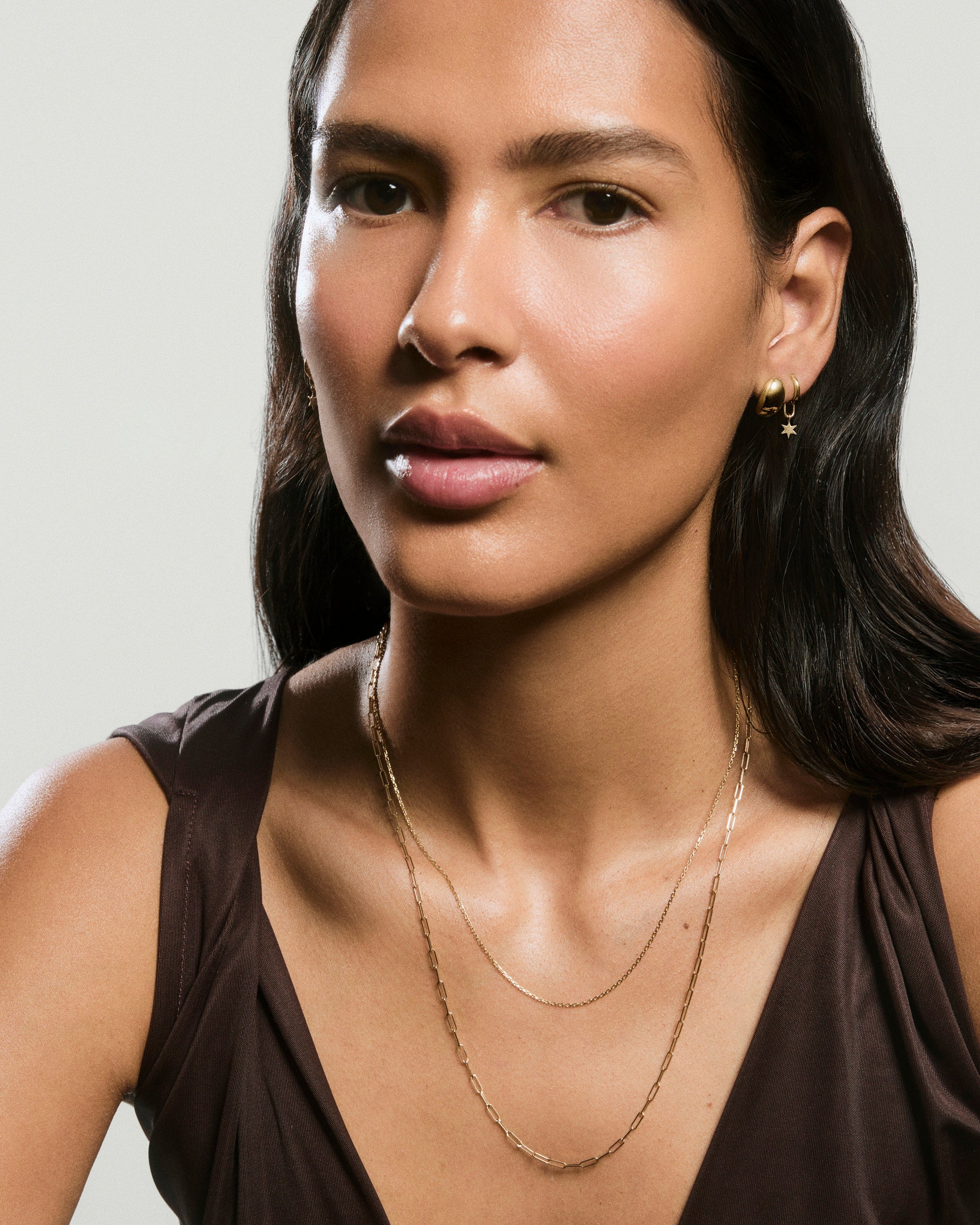 Young woman wears a sleeveless top, showcasing an Oval Link Chain Necklace with ovular links, perfect for adding charms or layering with other necklaces.