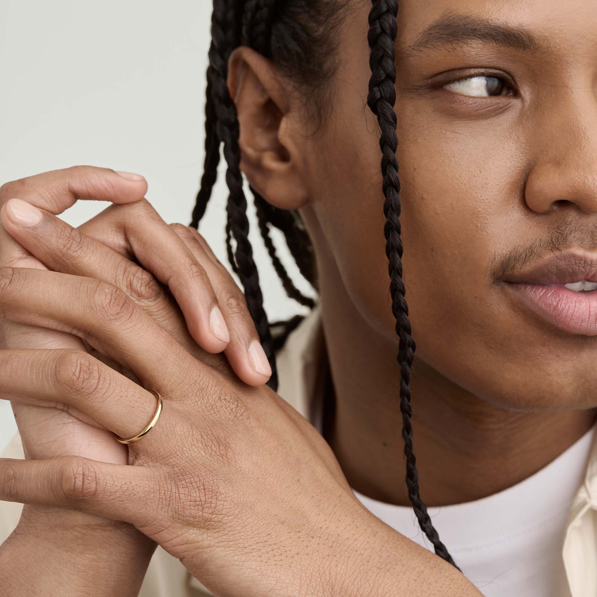 Man with braids clasping hands, showcasing the 2mm Curve Band on his finger, highlighting its lightweight and lasting design perfect for any new chapter.