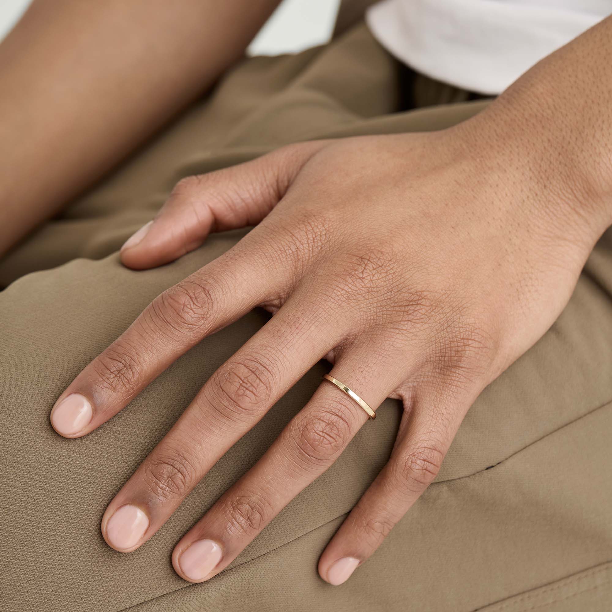 2mm Smooth Band on a person's finger, handcrafted in recycled 14k solid gold with streamlined edges, symbolizing an enduring bond or a timeless ring stack addition.